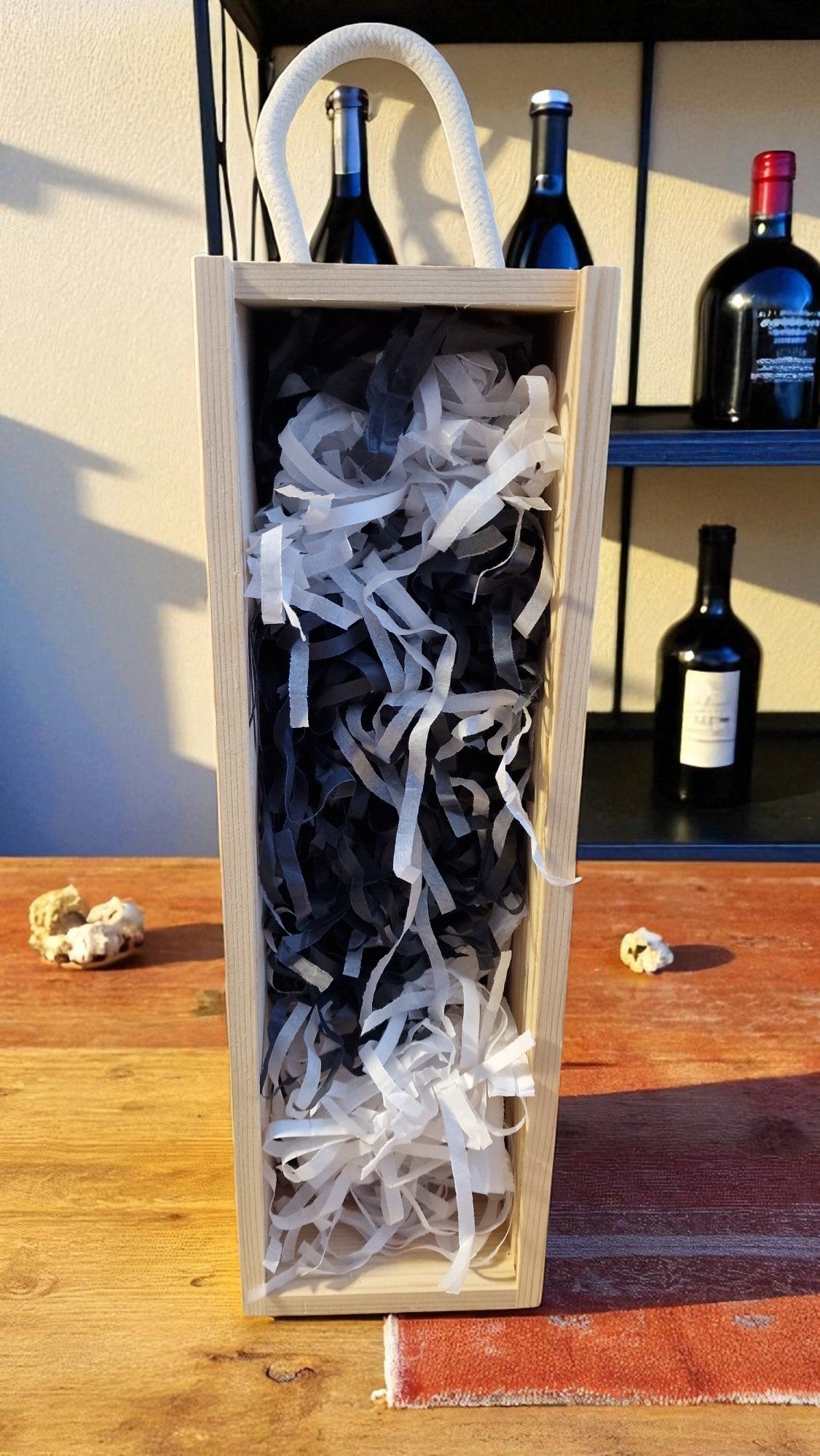 Wine bottle in a wooden box with white tissue paper on a wooden table.