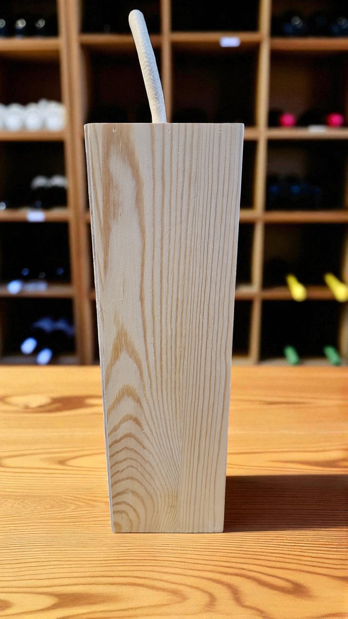 Wooden block with a metal rod on a wooden surface with blurred shelves in the background