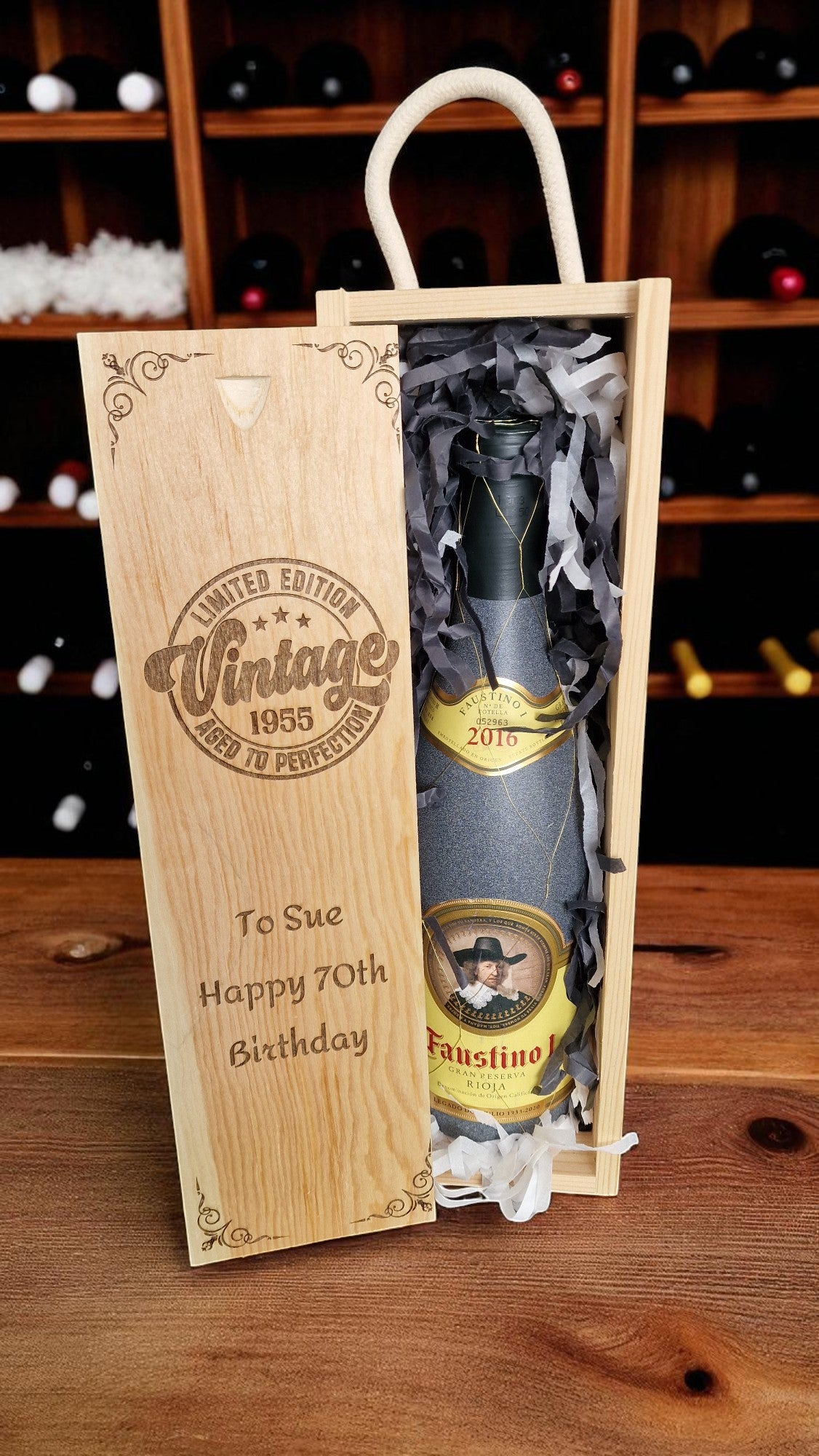 Wine bottle in a wooden gift box with personalized message on a wooden surface.