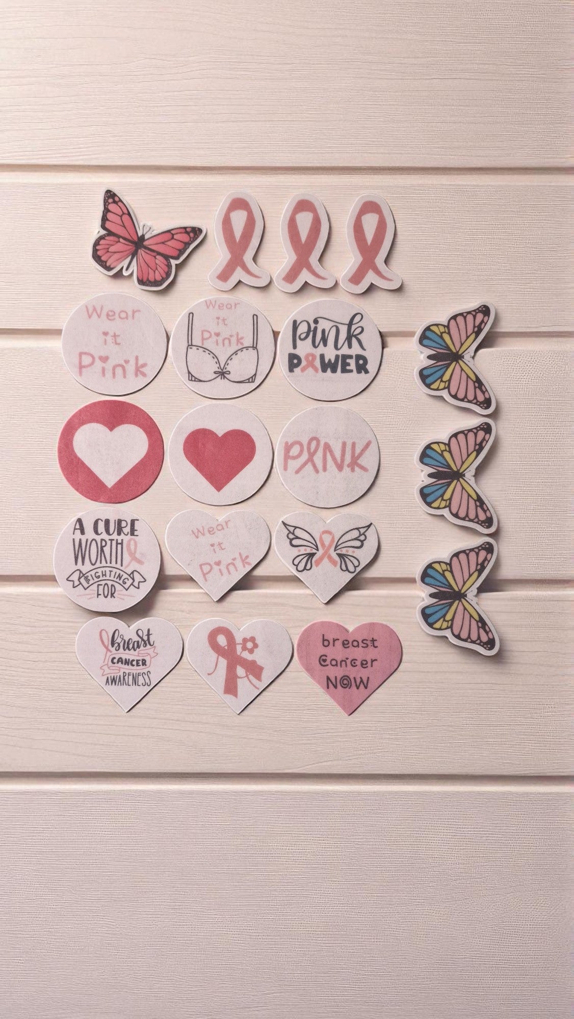 Collection of pink-themed stickers and butterflies on a wooden background