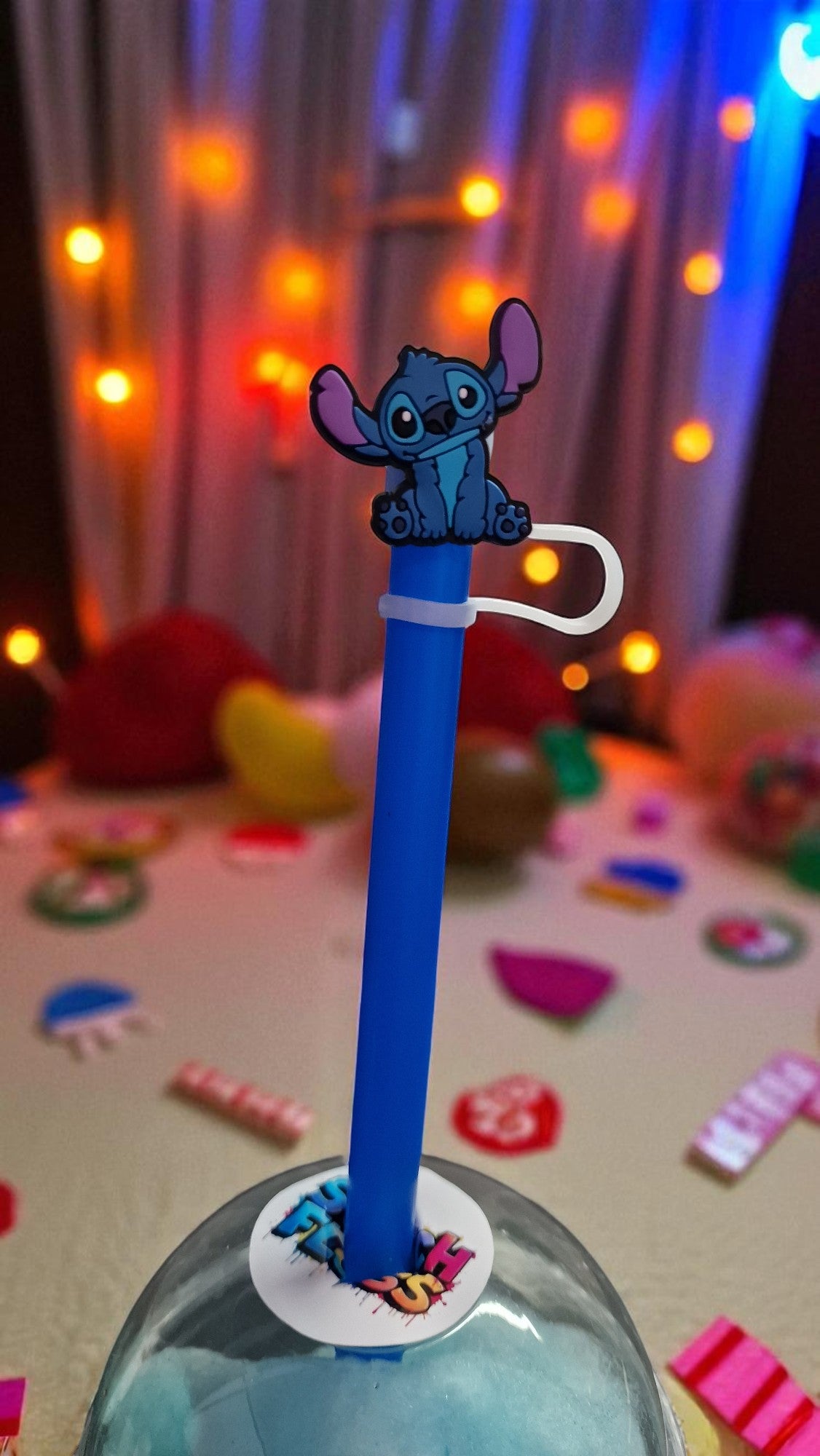 Blue straw with a cartoon character on top against a colorful, blurred background