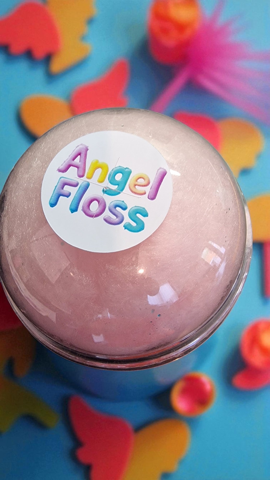 Pink ball with 'Angel Floss' label on a colorful butterfly background