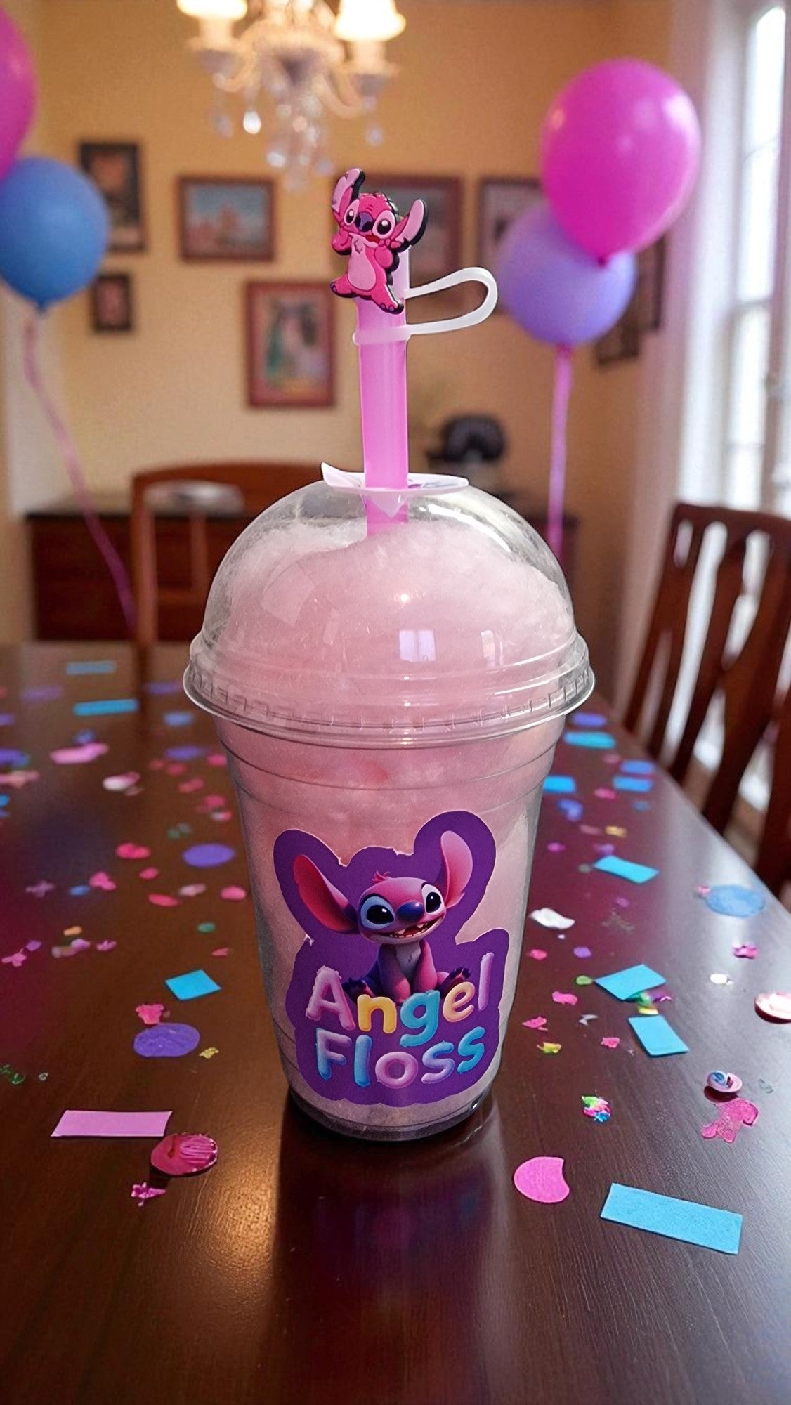 Pink drink with a straw holder on a table with confetti and balloons