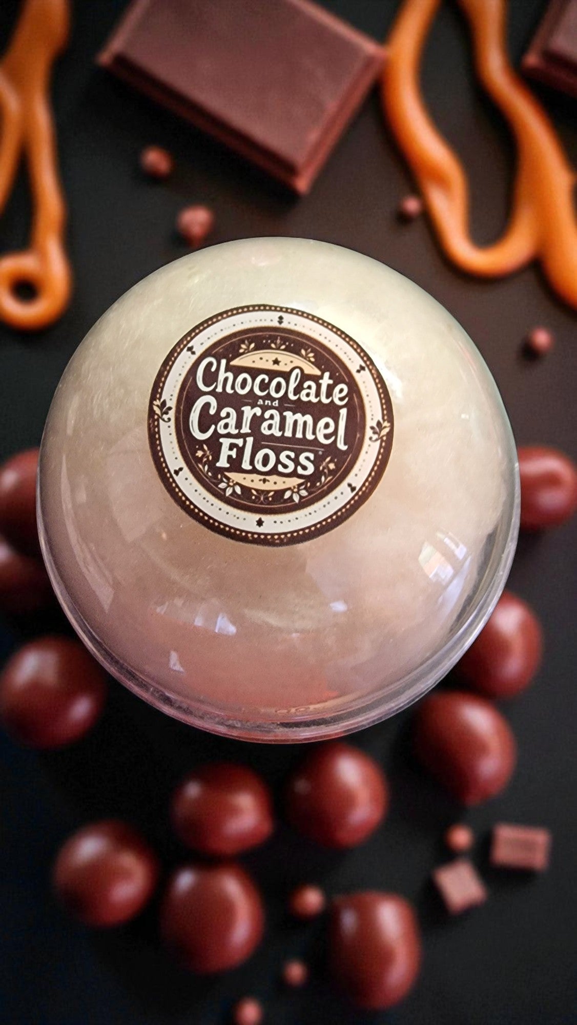 Ball of chocolate caramel floss with a label surrounded by chocolate pieces on a dark background