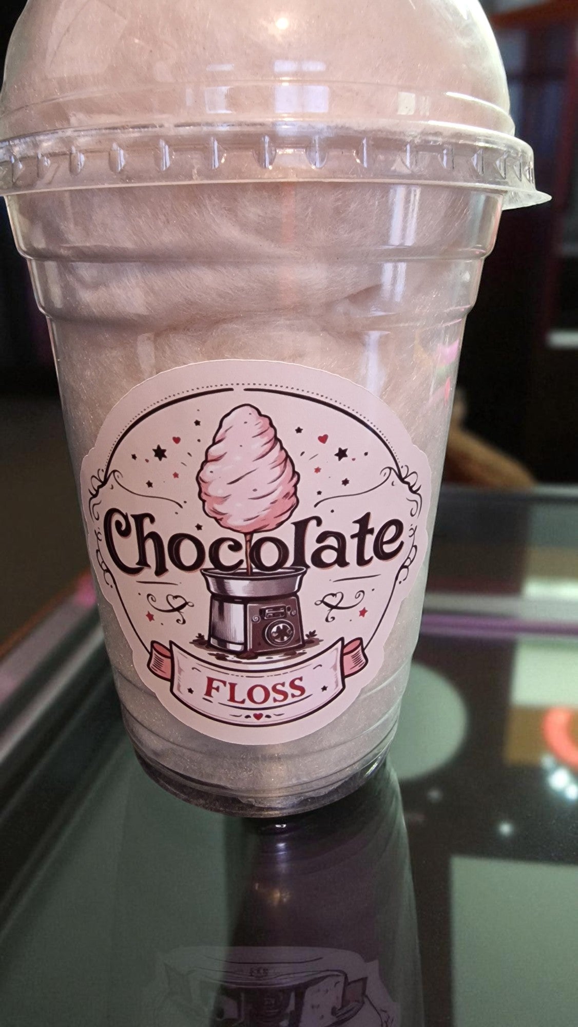 Clear plastic cup with a label reading 'Chocolate Floss' on a reflective surface.