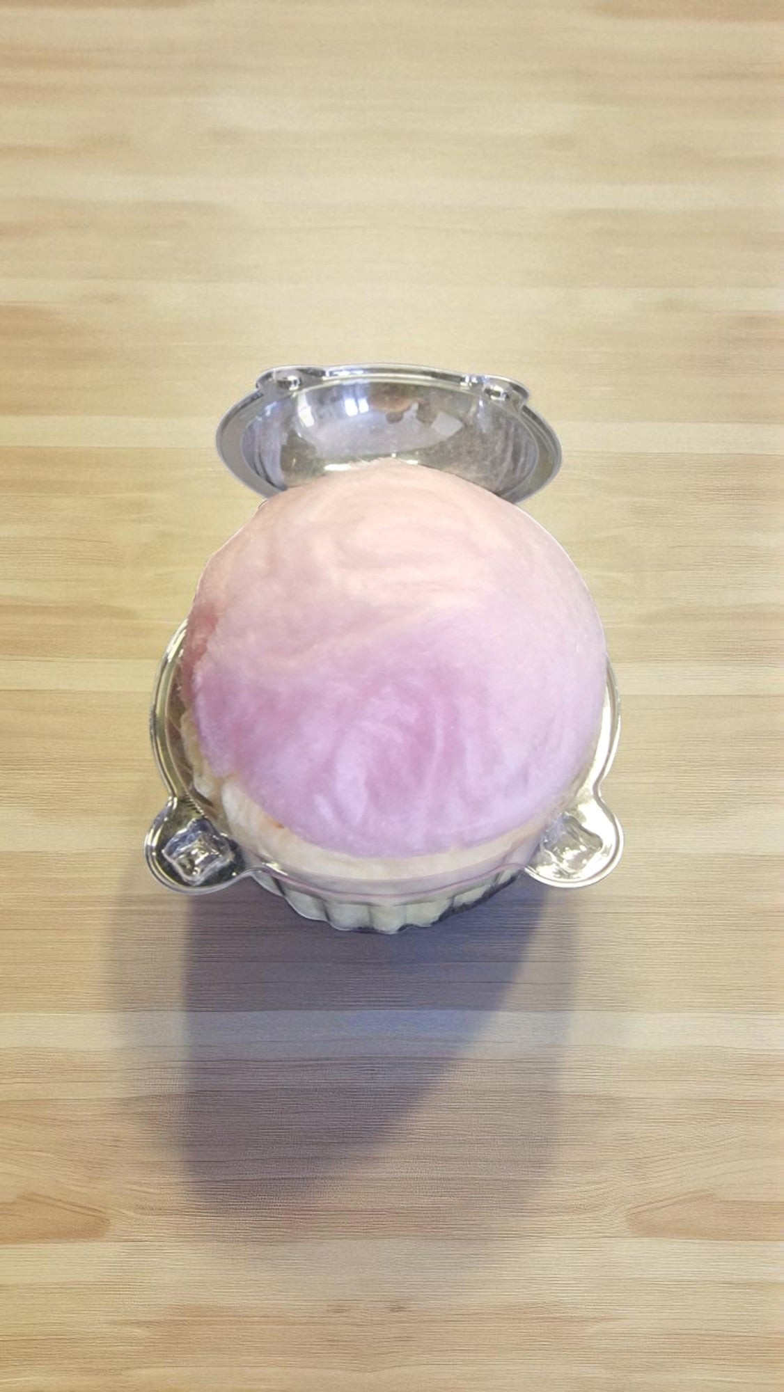 Pink bath bomb with silver ring on a wooden surface