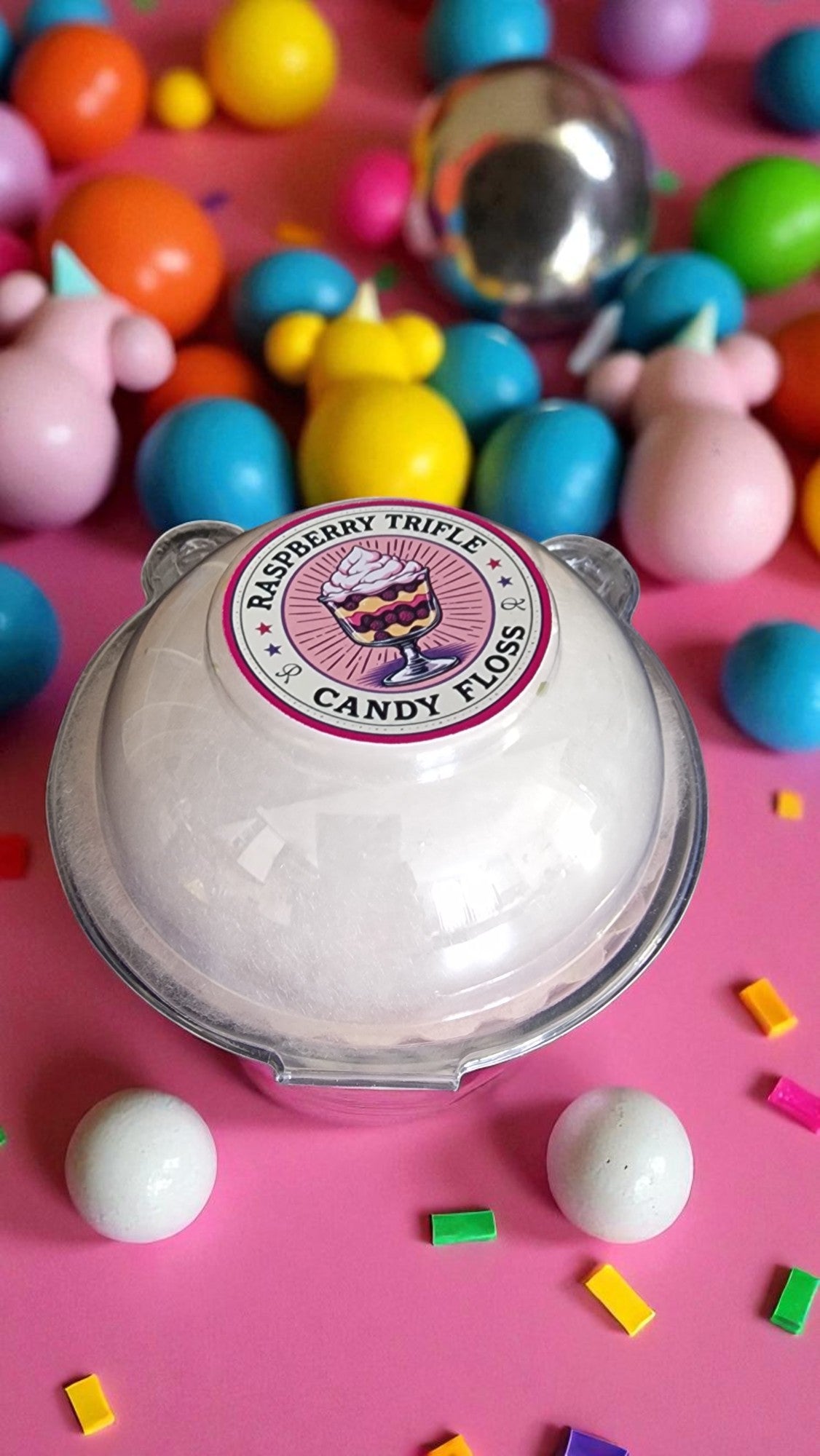 Candy floss container with colorful candies on a pink background