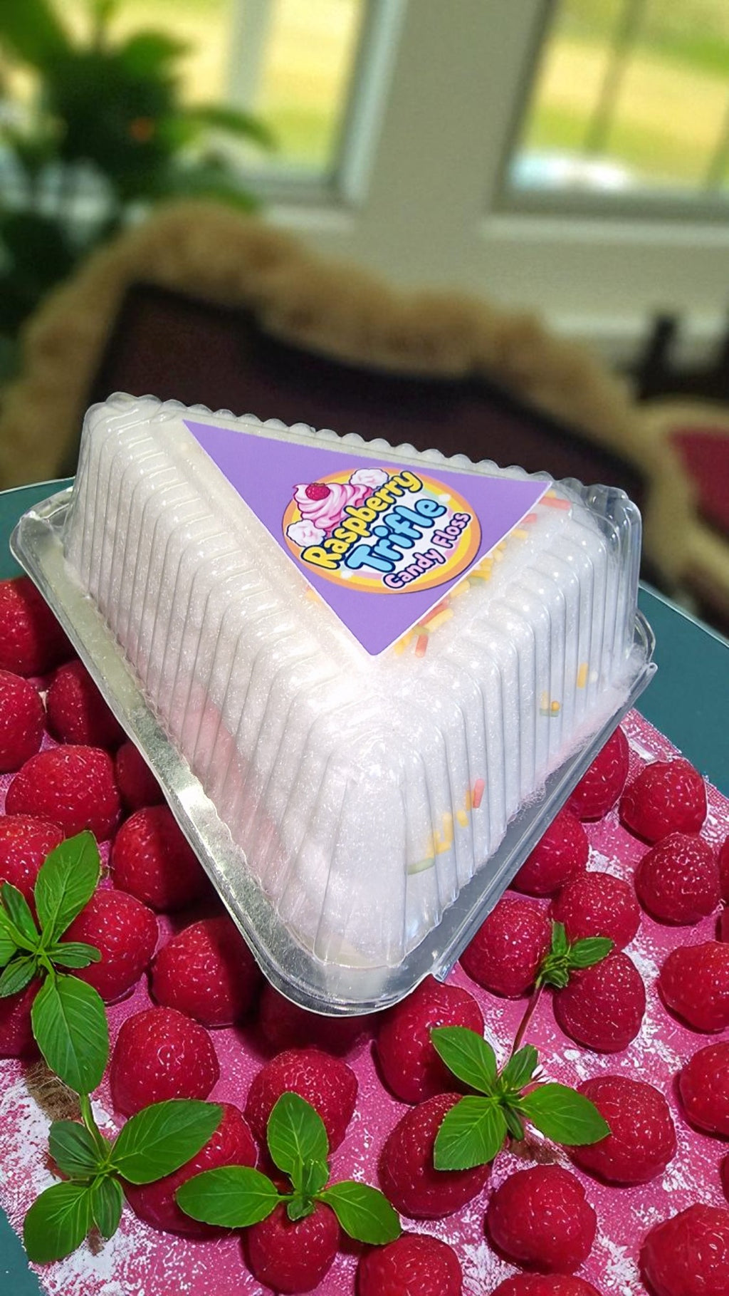 Packaged dessert on a bed of raspberries with a blurred indoor background