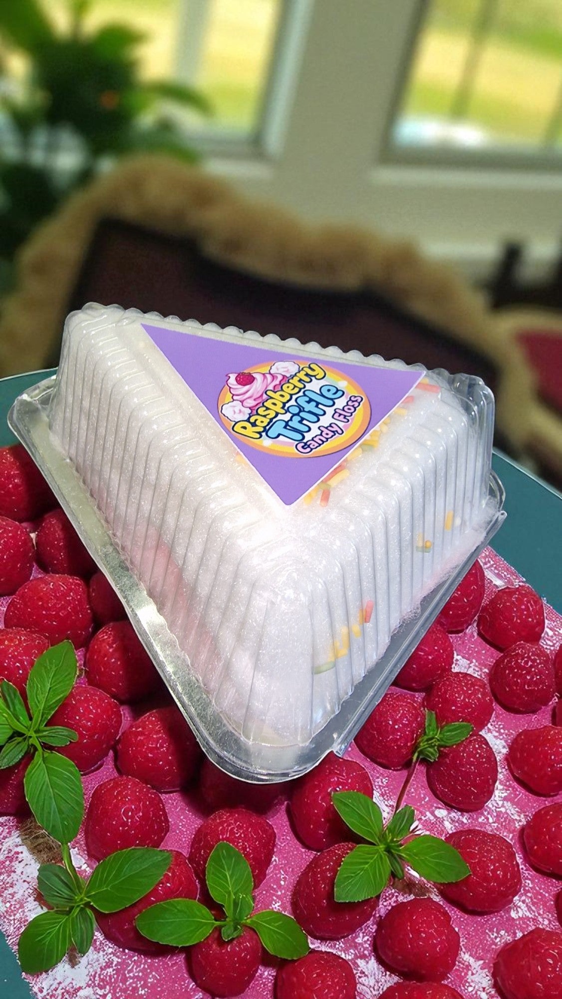 Packaged dessert on a bed of raspberries with a blurred indoor background