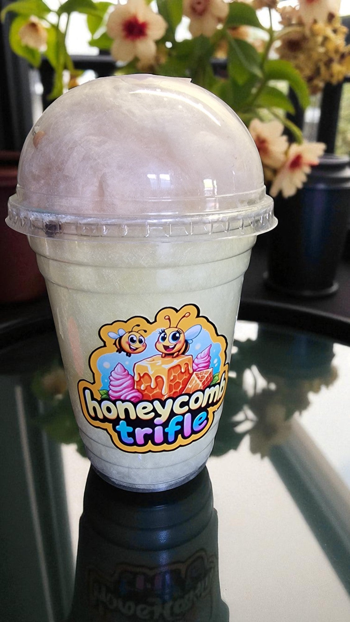 Ice cream dessert in a transparent container with a colorful label on a reflective surface.