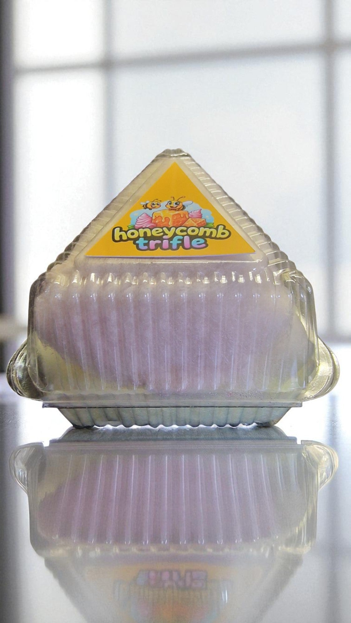 Honeycomb trifle container with a colorful label on a reflective surface.