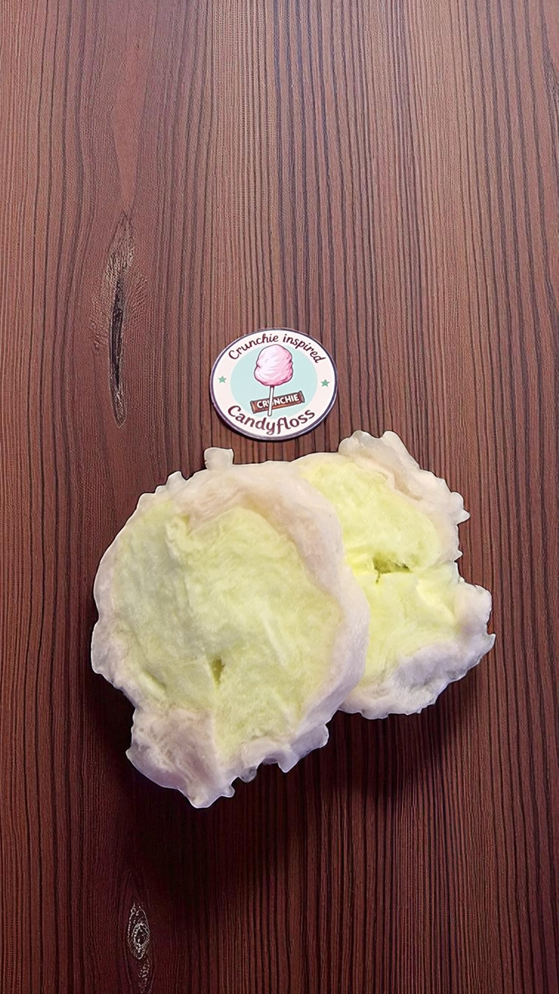 Light-colored bath bomb on a wooden surface with a visible brand label.