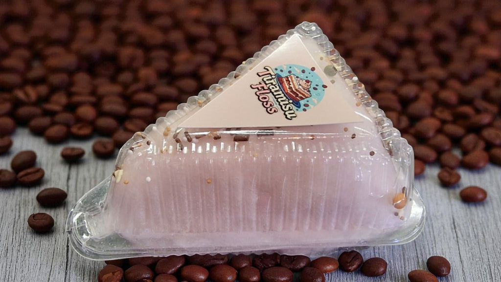 Triangular dessert in a clear plastic packaging with coffee beans on a wooden surface