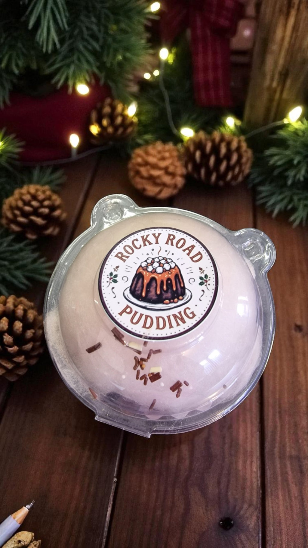 Rocky Road pudding in a transparent container on a wooden surface with Christmas decorations.