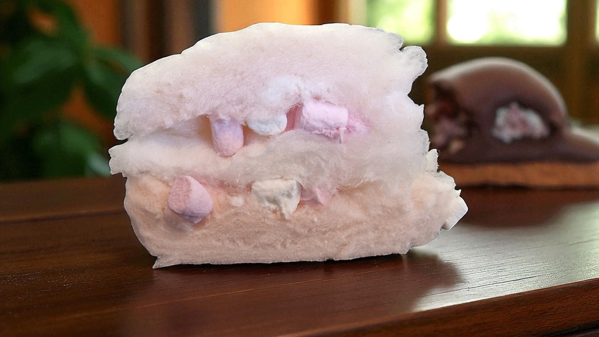 Pink cotton candy on a wooden surface with a blurred background