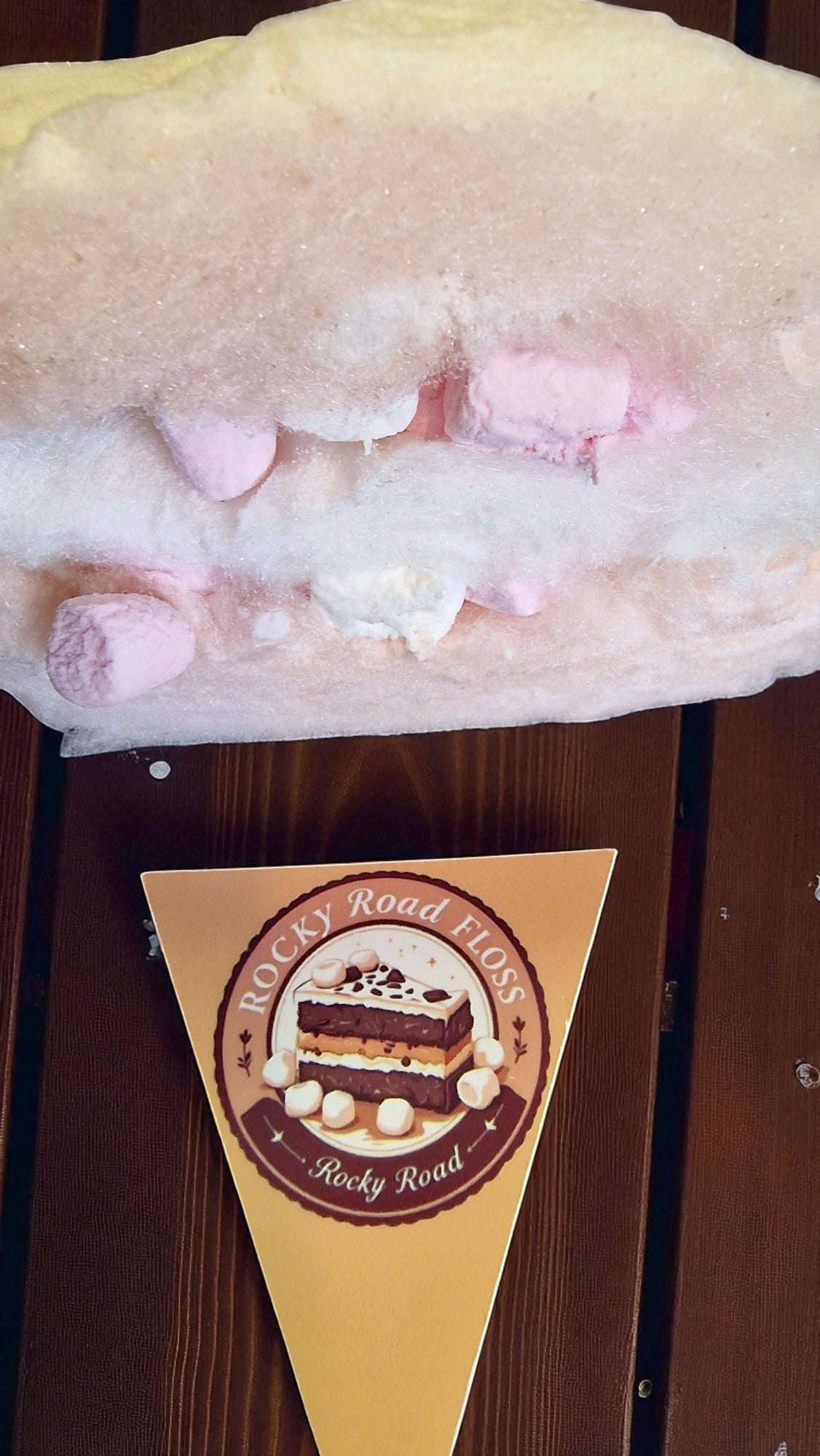 Marshmallow dessert with pink and white marshmallows on a wooden surface, featuring a Rocky Road-themed cone.