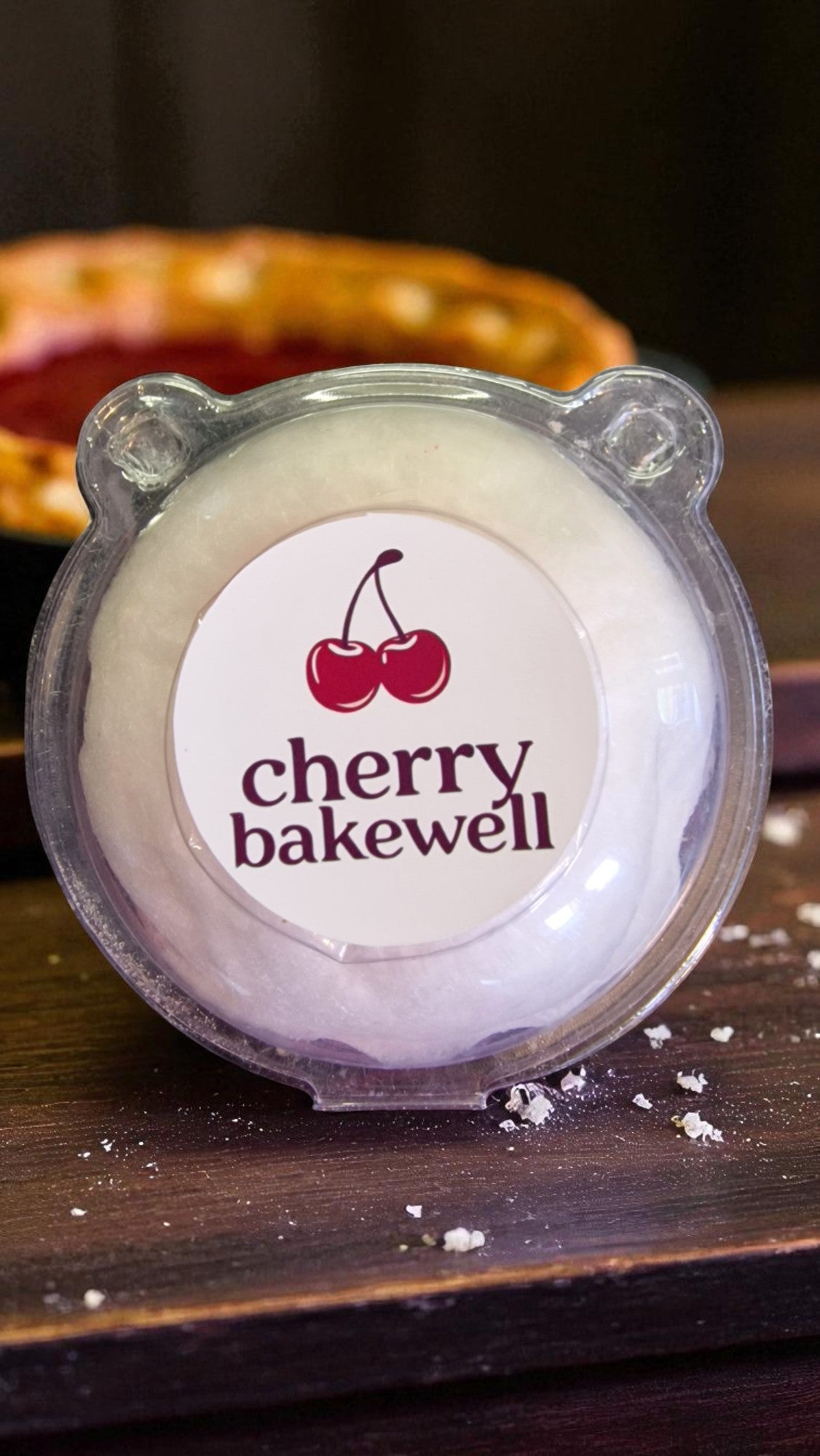 Cherry Bakewell product with a cherry logo on a wooden surface