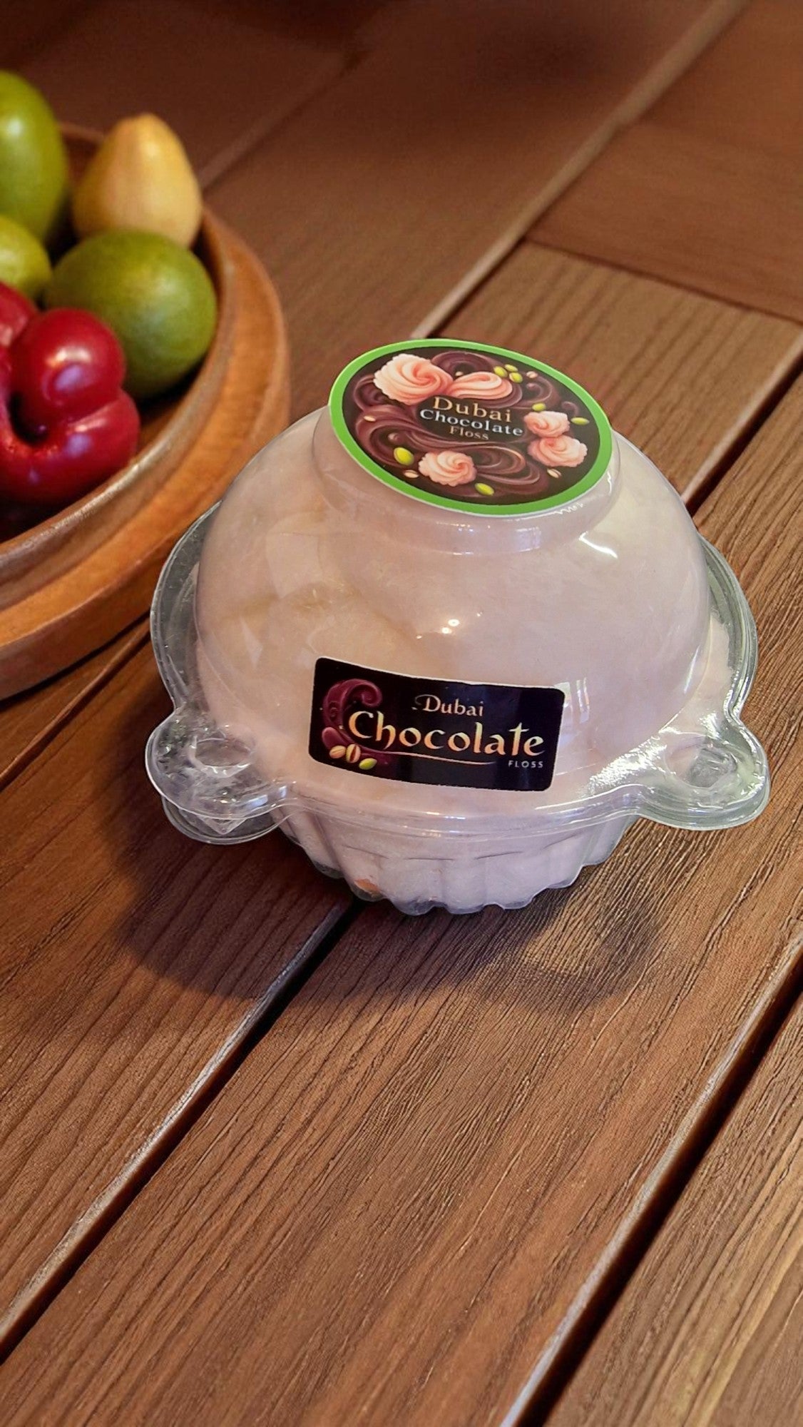 Dessert in a clear container with 'Dubai Chocolate' branding on a wooden surface.