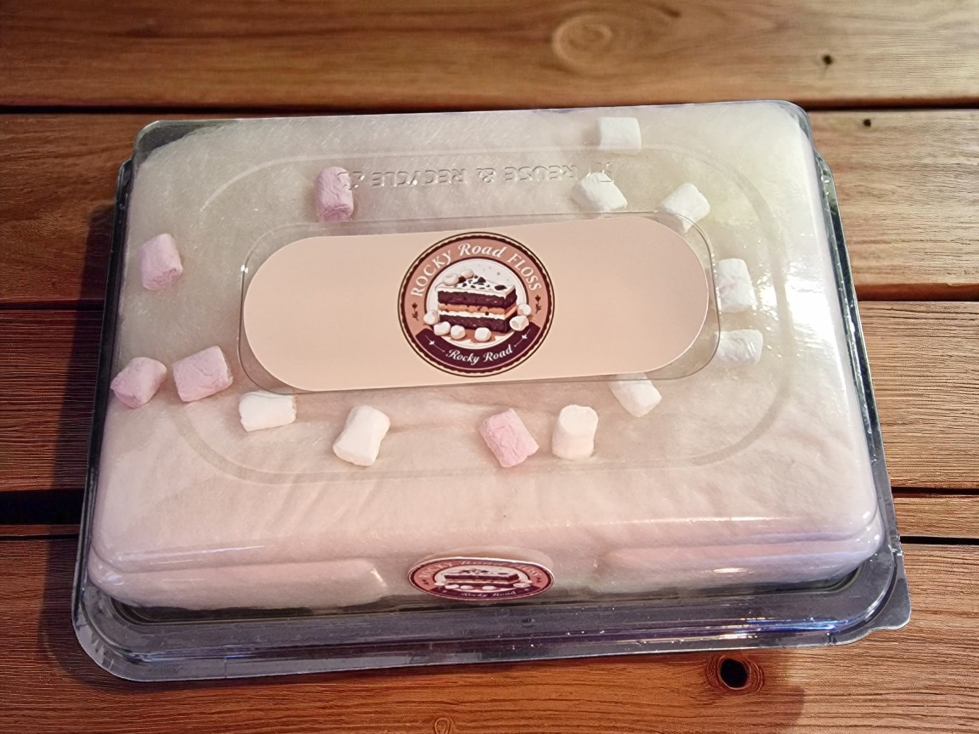 Packaged dessert with pink and white marshmallows on a wooden surface