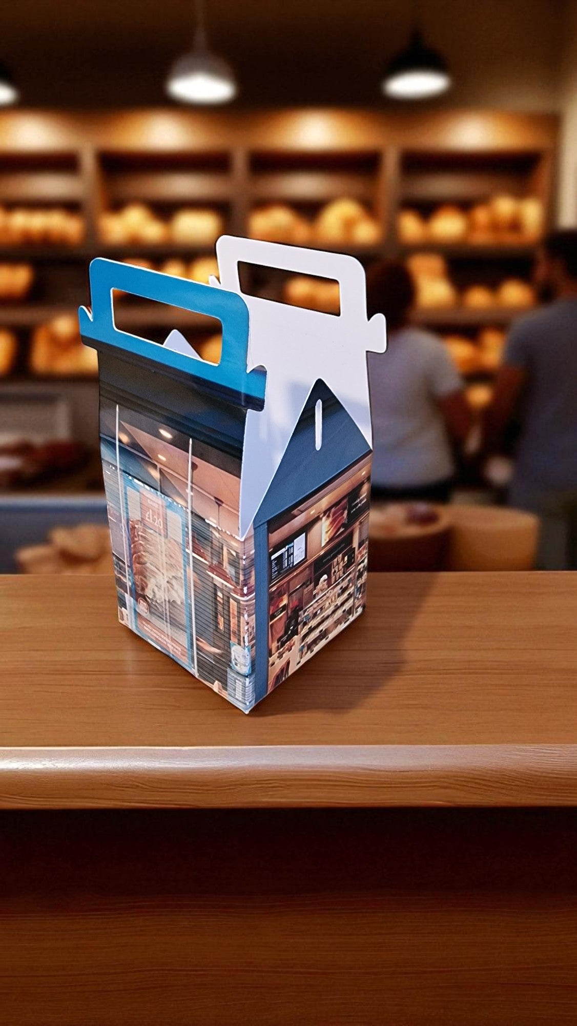 Cardboard box with a handle on a wooden table in a bakery setting