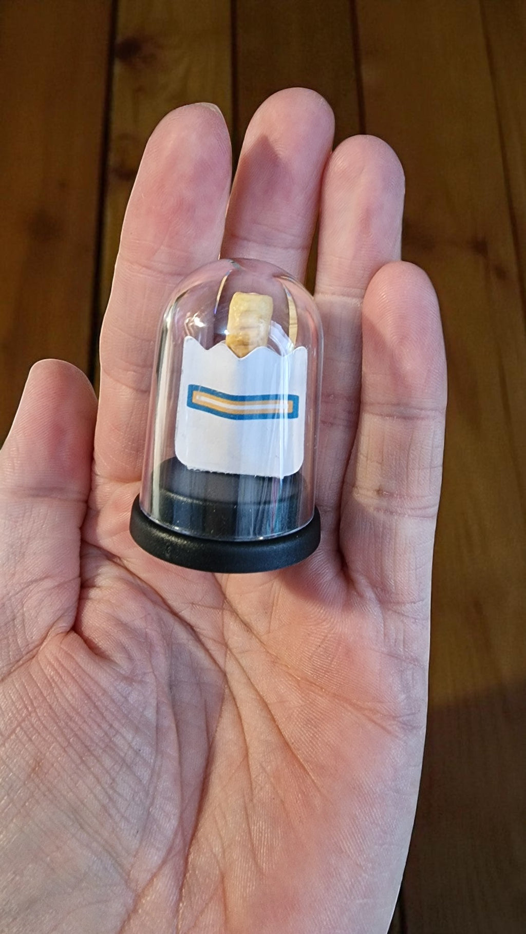 Small transparent container with a label held in a hand against a wooden background