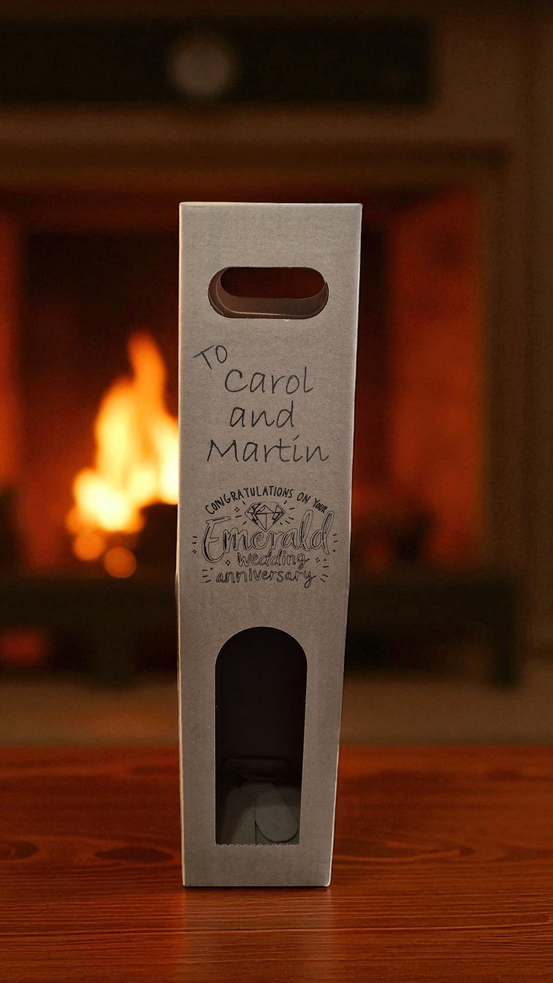 Wine bottle box with personalized text in front of a fireplace