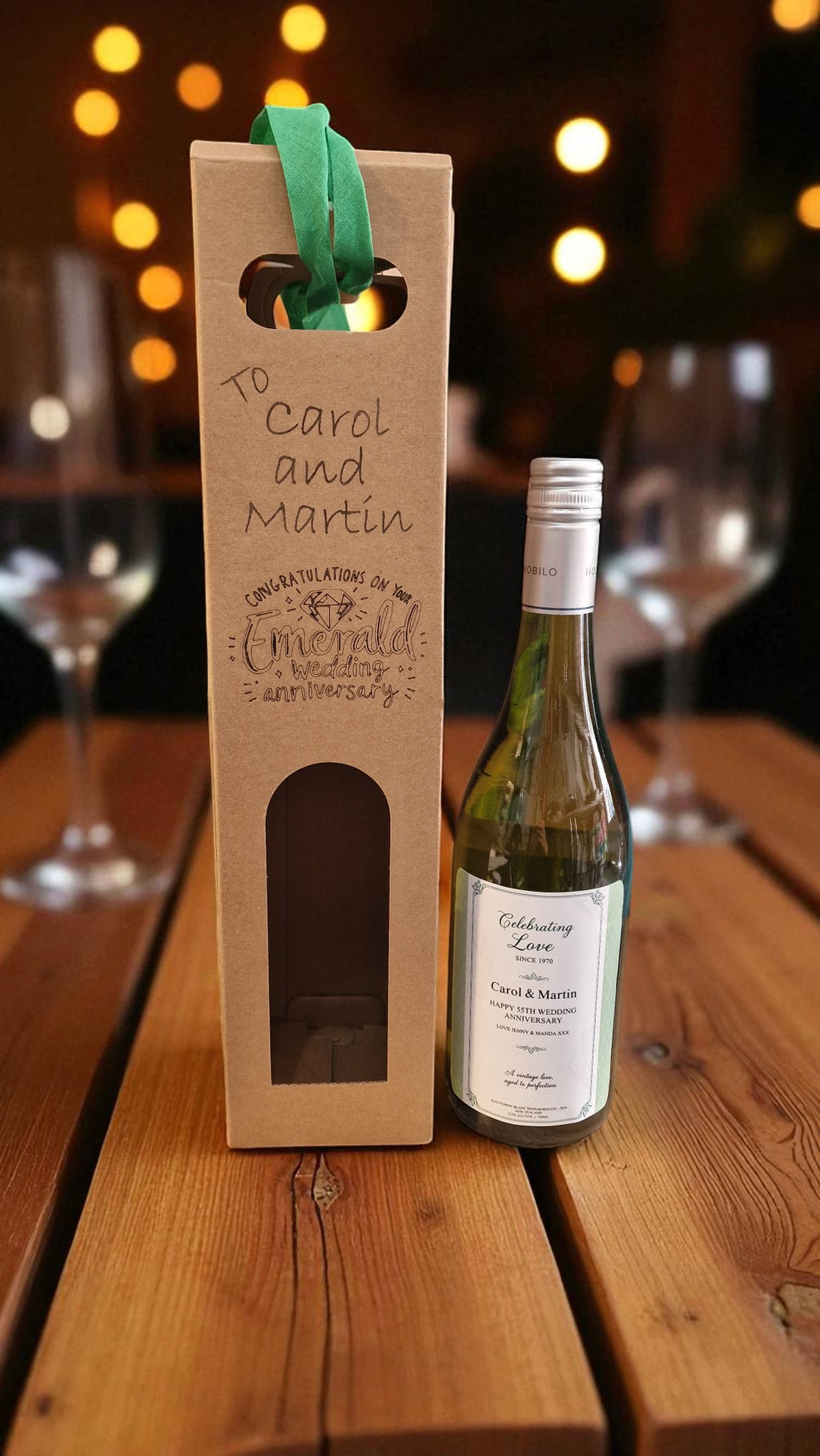 Wine bottle with a personalized wooden box on a wooden table with blurred lights in the background.