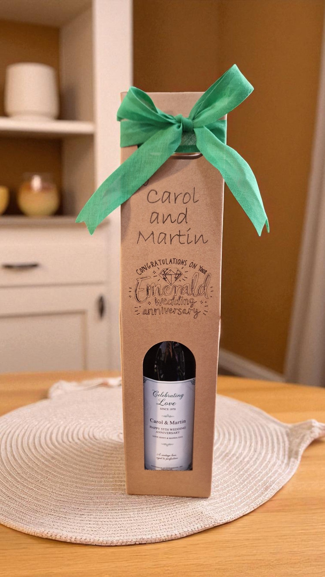 Wine bottle gift box with a green ribbon on a wooden table.