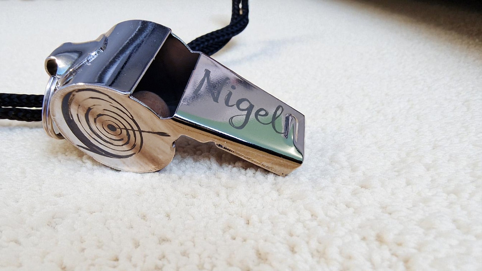 Metallic whistle with 'Miguel' engraved on a white surface
