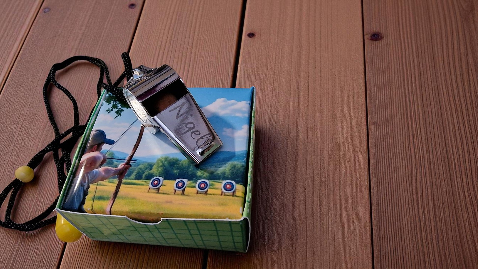 Whistle on a box with archery design on a wooden surface