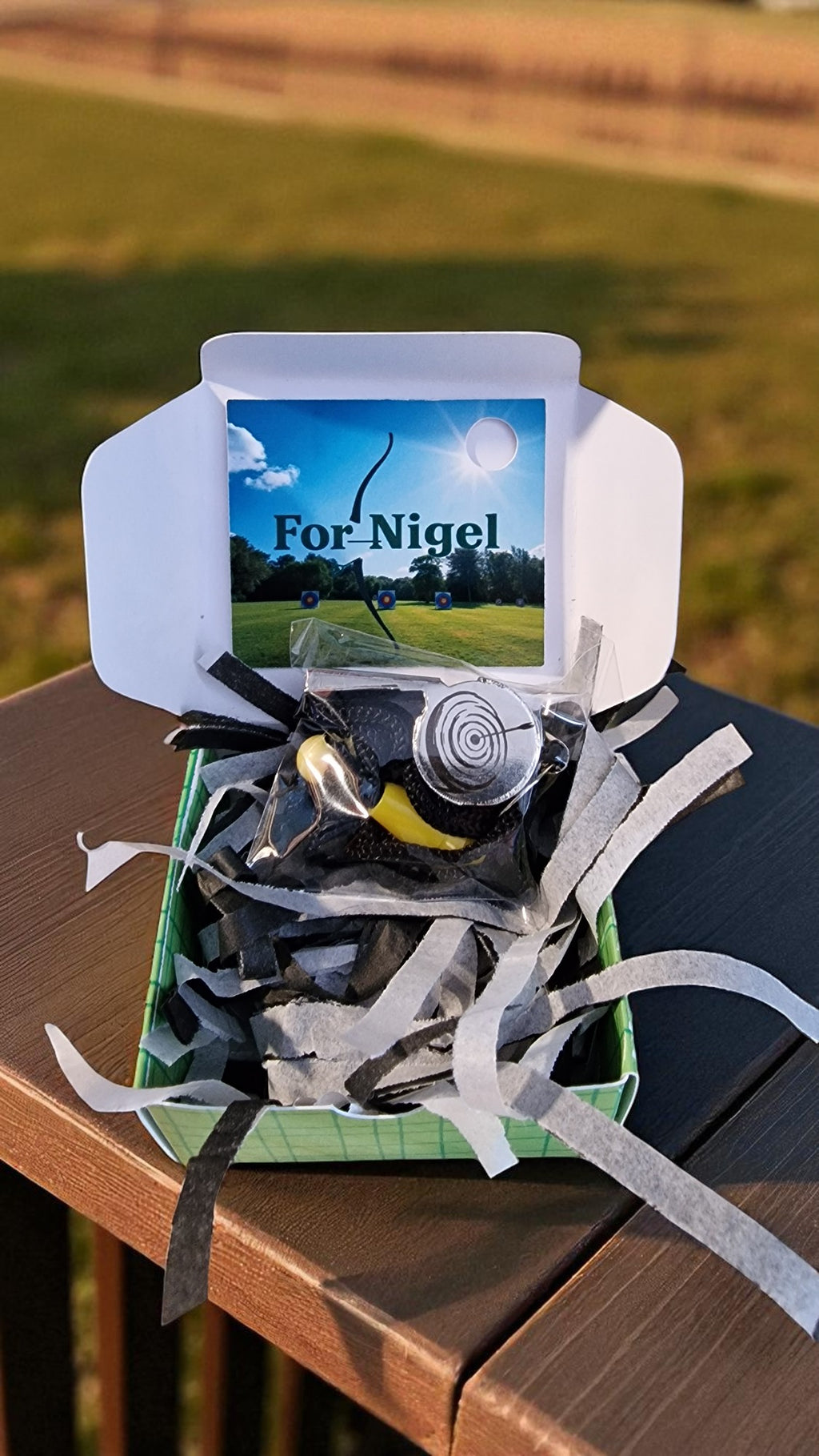 Golf-themed gift set with a card labeled 'For Nigel' on a wooden surface.