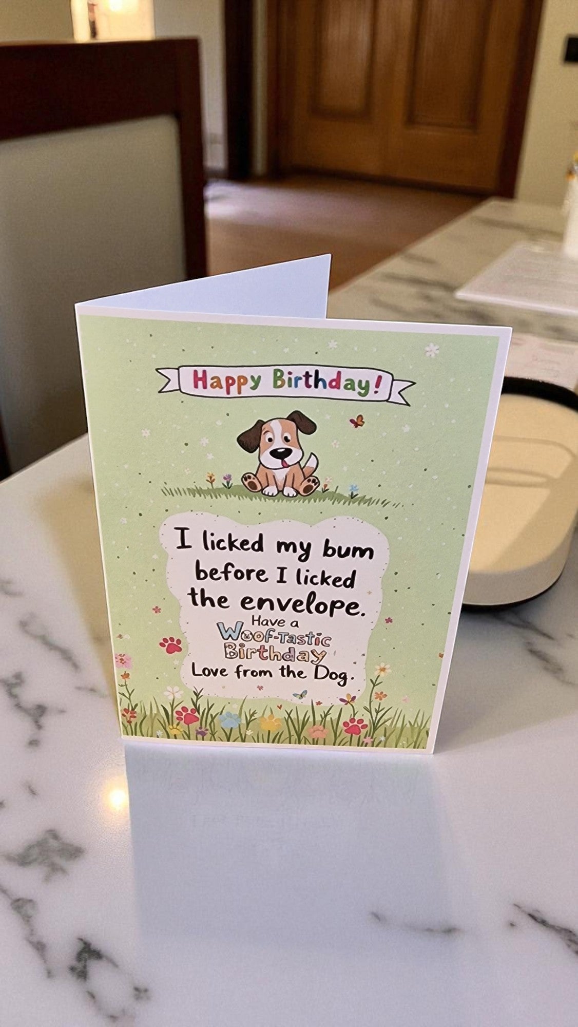 Birthday card with a dog illustration and humorous text on a marble surface.