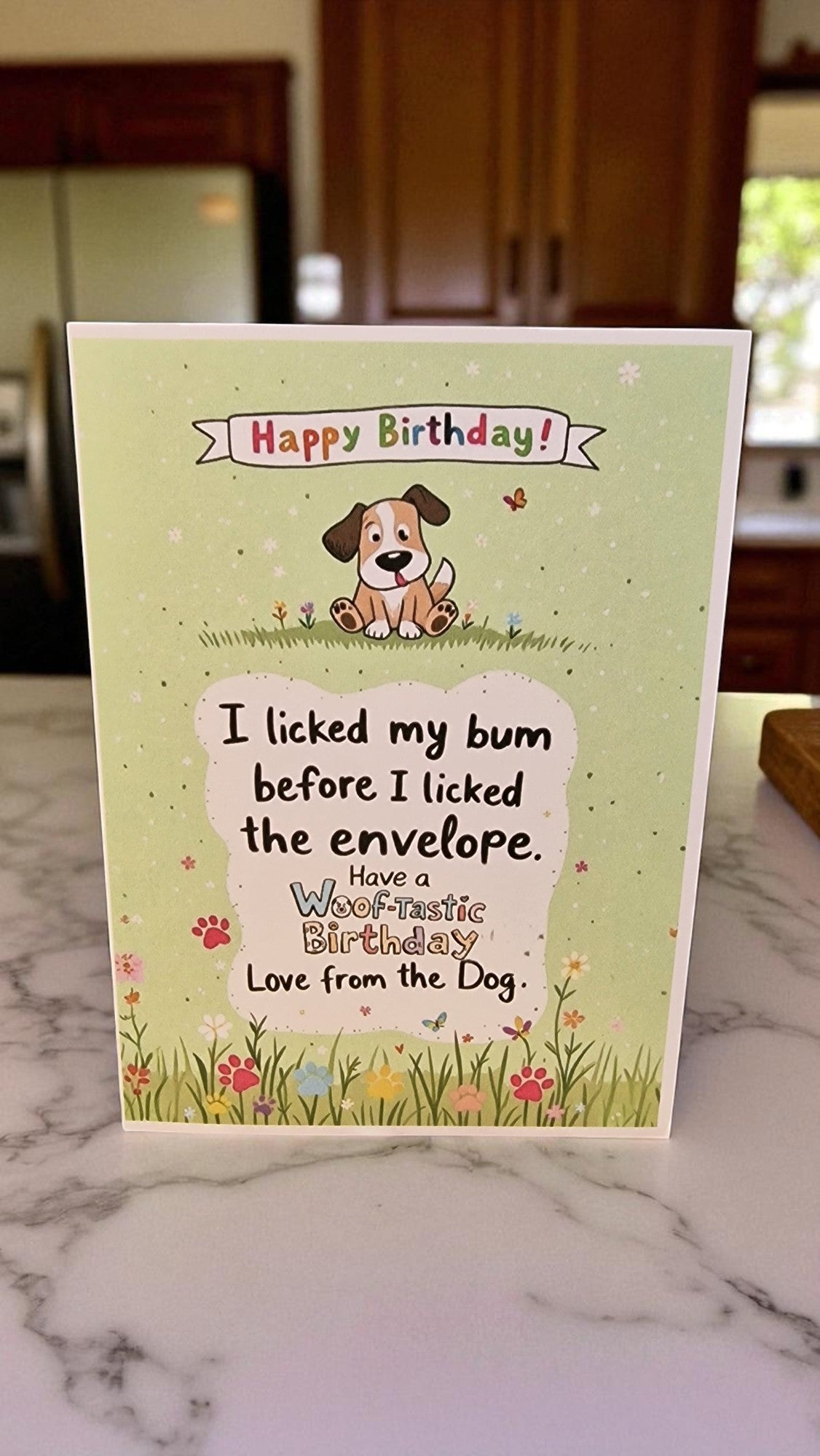 Birthday card with a dog illustration and humorous text on a marble surface.