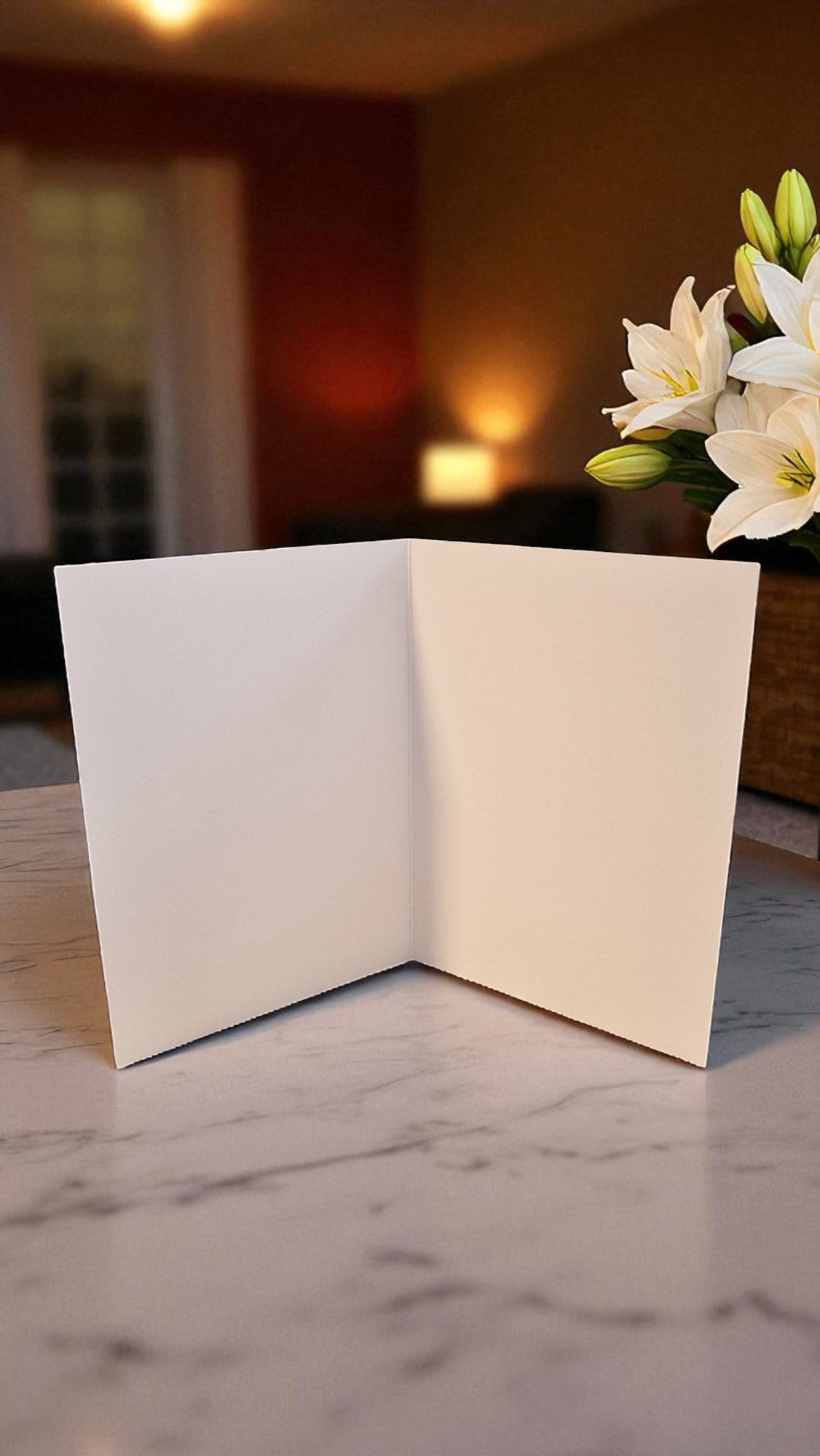 Open beige card on a marble surface with flowers in the background
