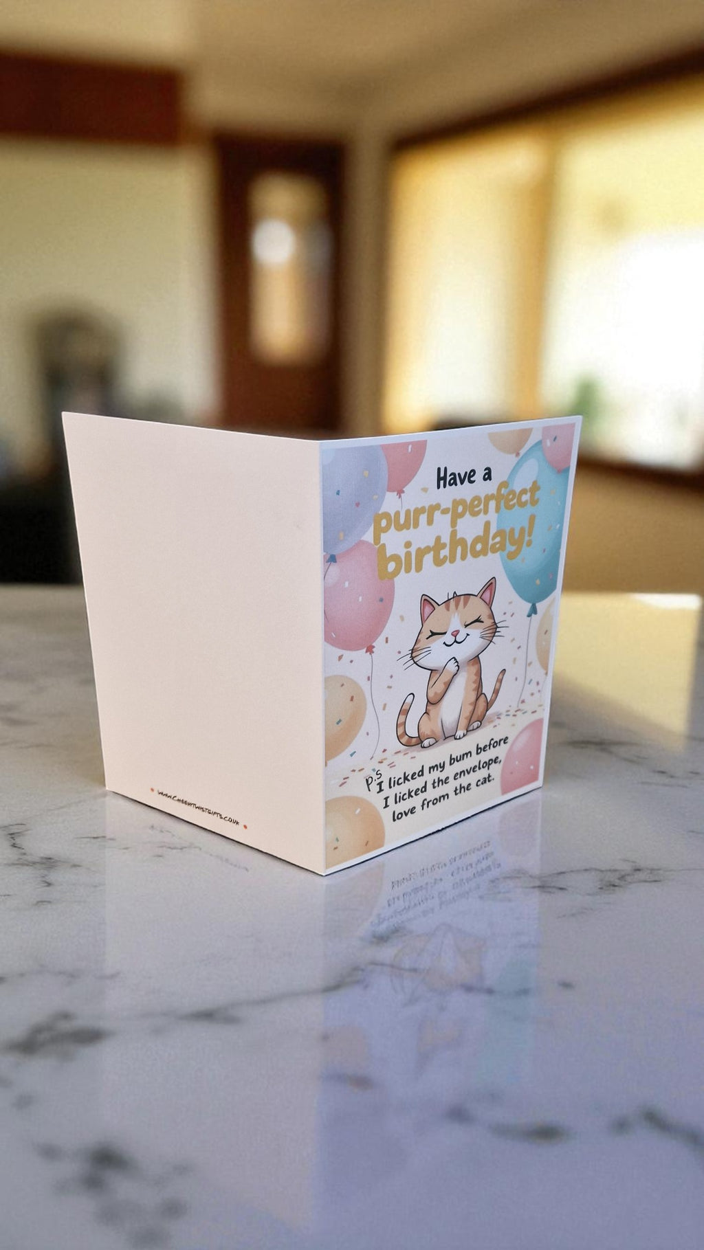Greeting card with a cat illustration and 'purr-perfect birthday!' text on a marble surface.
