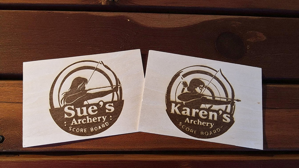 Two wooden scoreboards with archery designs and names 'Sue's Archery' and 'Karen's Archery' on a wooden surface.