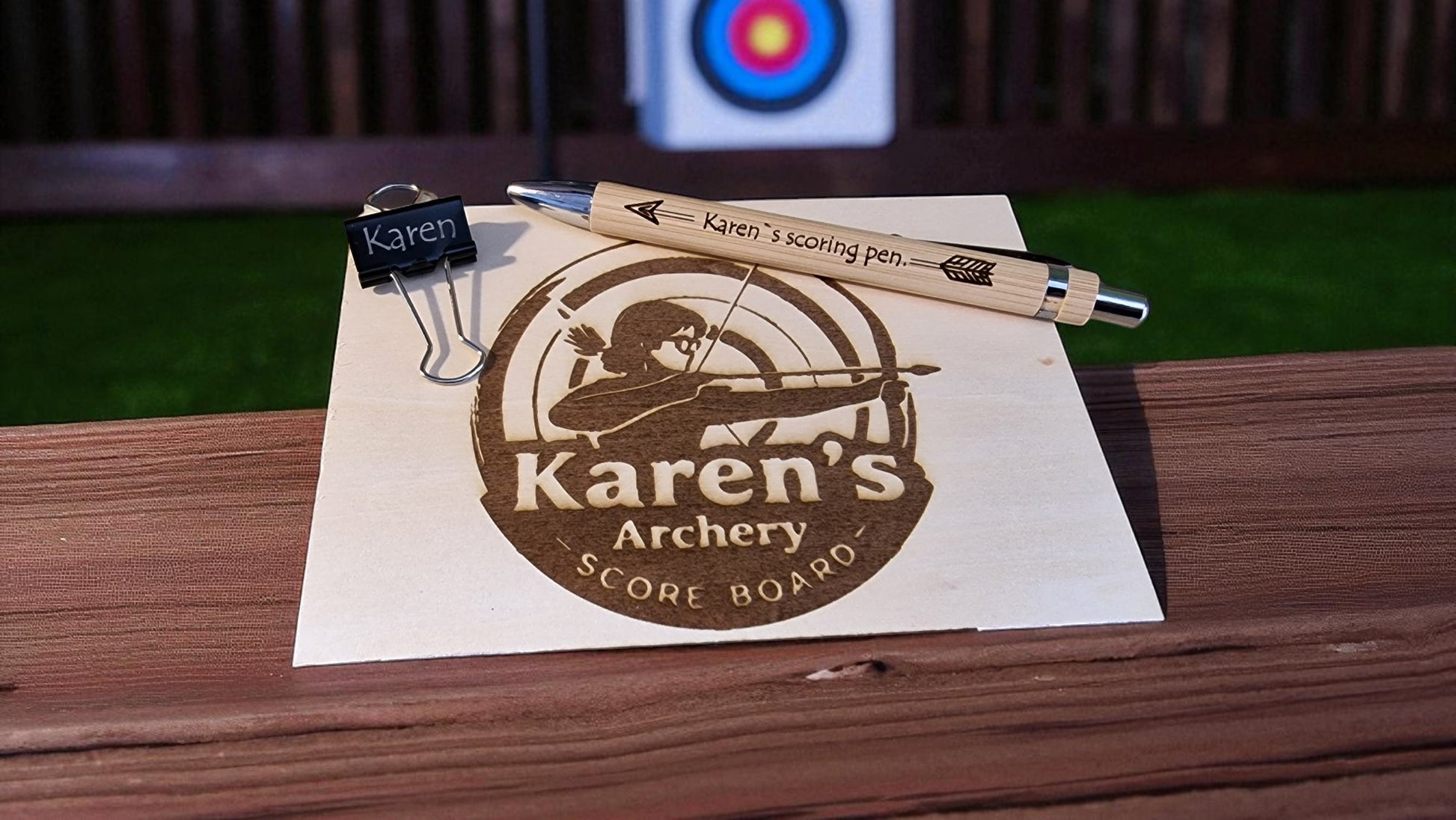 Scoreboard and scoring pen with 'Karen's Archery' branding on a wooden surface.