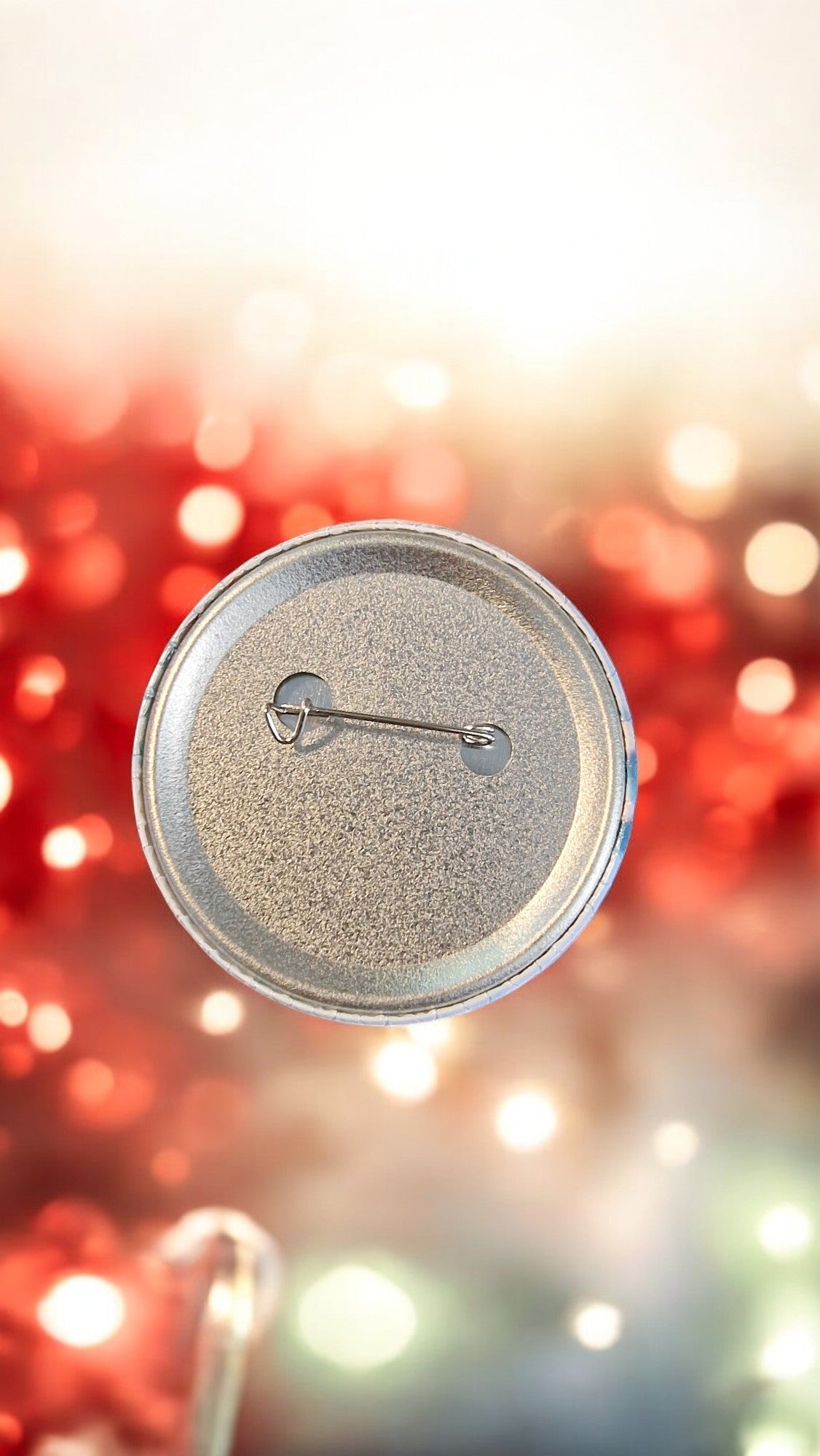 Silver button badge on a blurred festive background with red and green lights