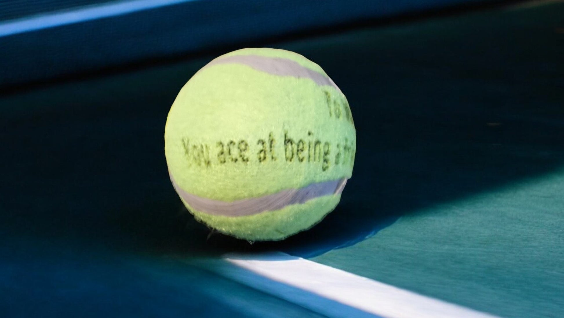 Tennis ball with text on a tennis court