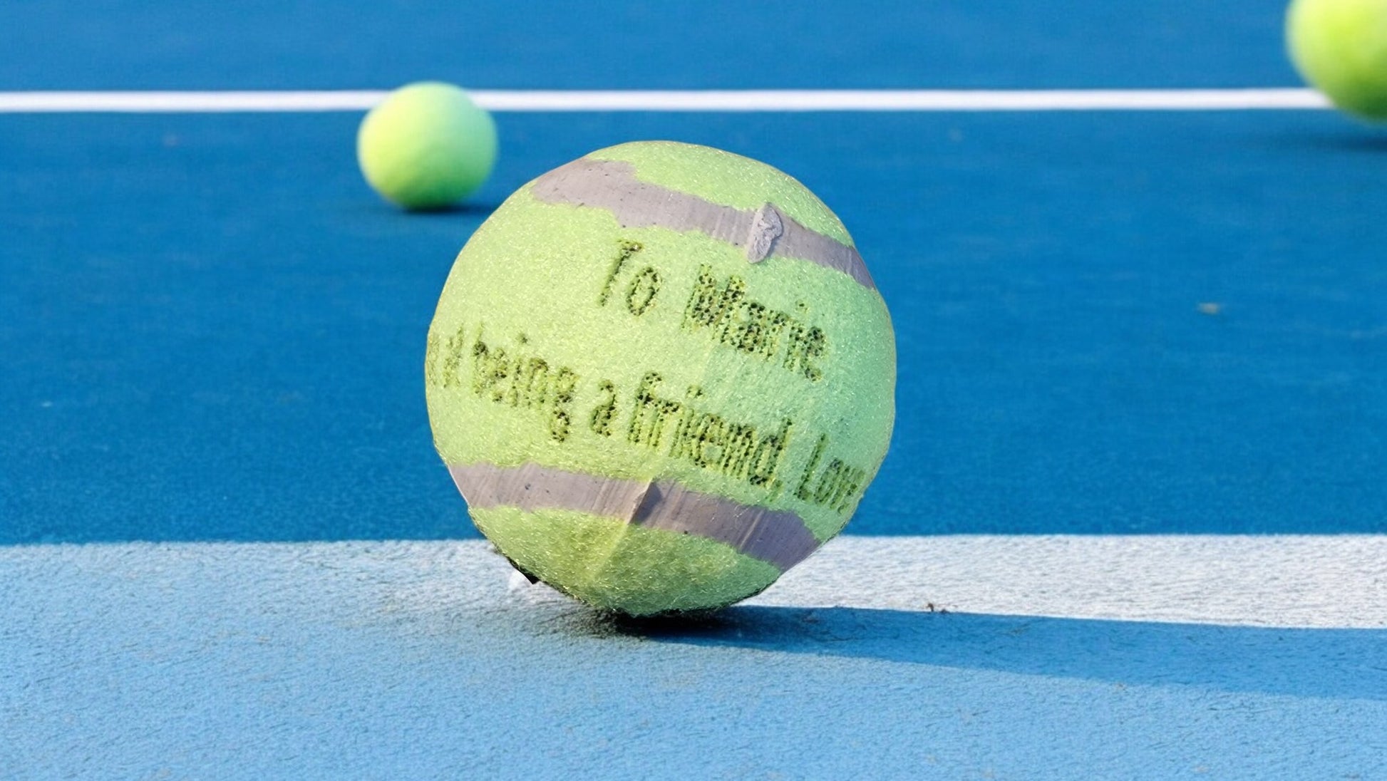 Tennis ball with text on a blue tennis court