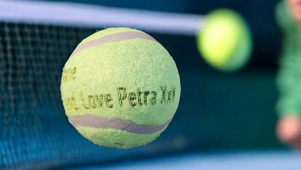 Tennis ball with 'Petra X' branding on a tennis court