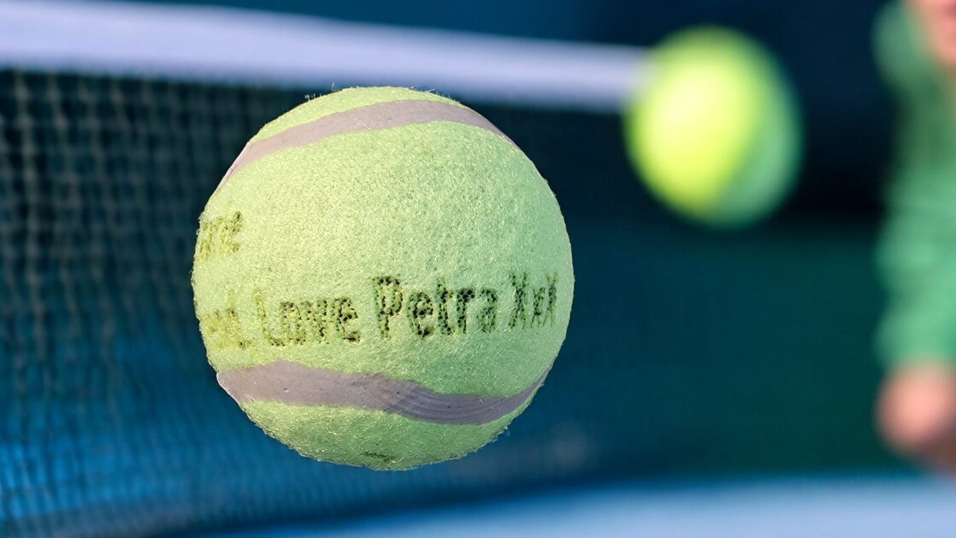 Tennis ball with 'Petra X' branding on a tennis court