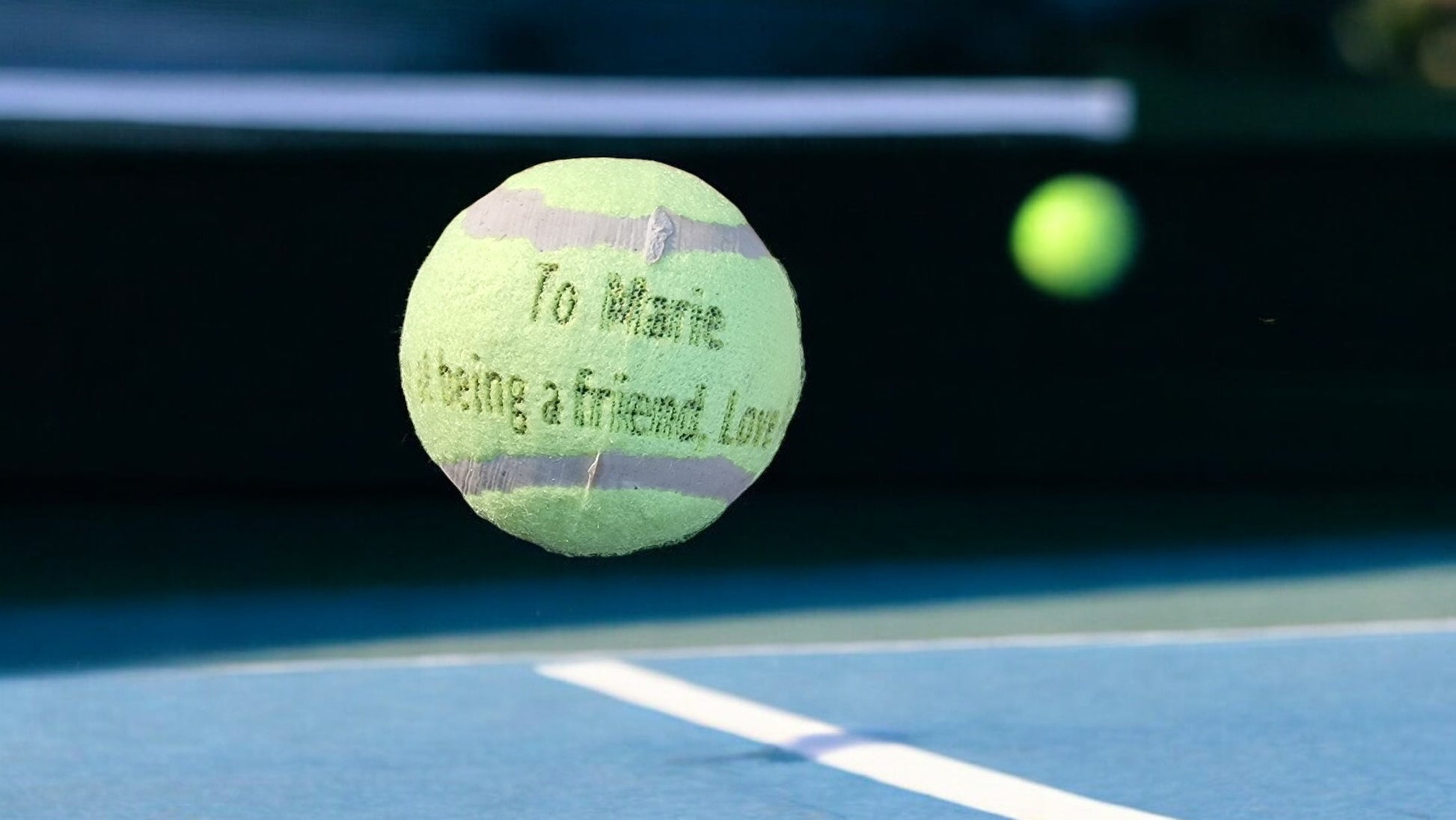 Tennis ball with text on a tennis court