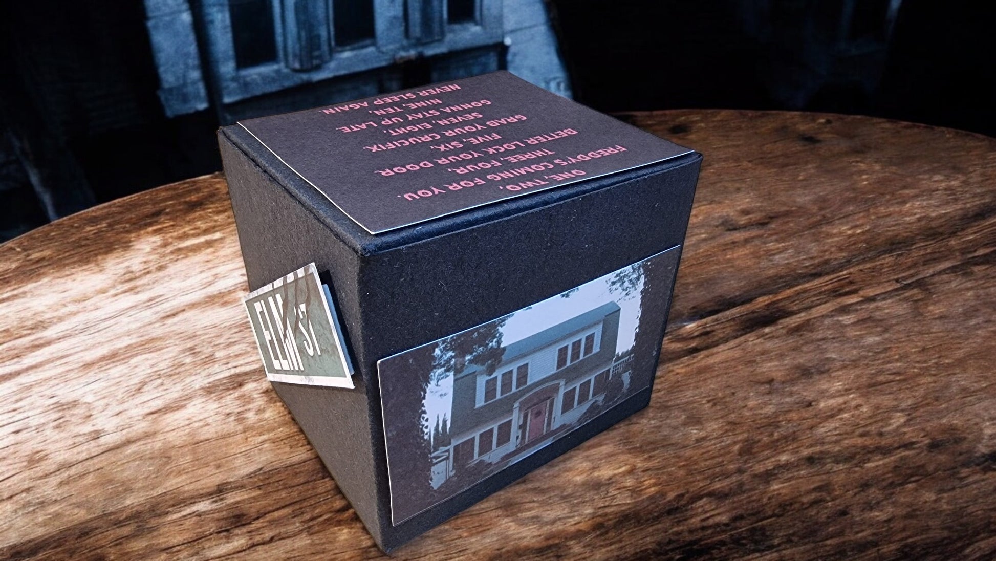 Black box with a reflective surface showing a house image on a wooden table