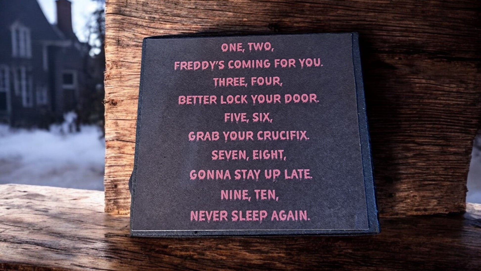 Text on a black card with pink letters on a wooden surface