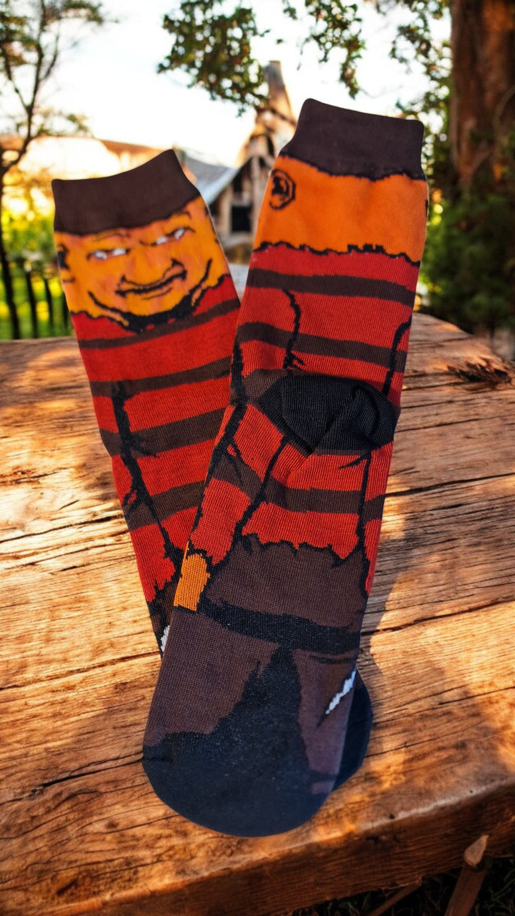 Pair of red and brown striped socks with a face design on a wooden surface.