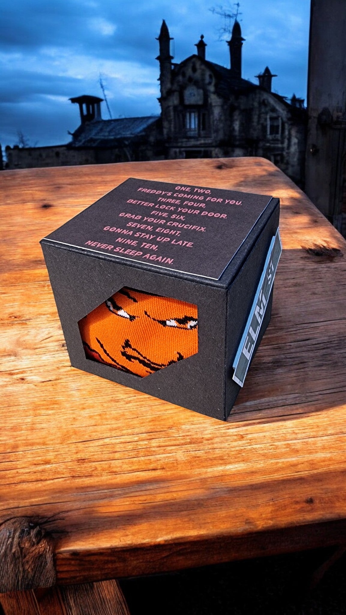 Black box with an orange mask on a wooden surface at night.