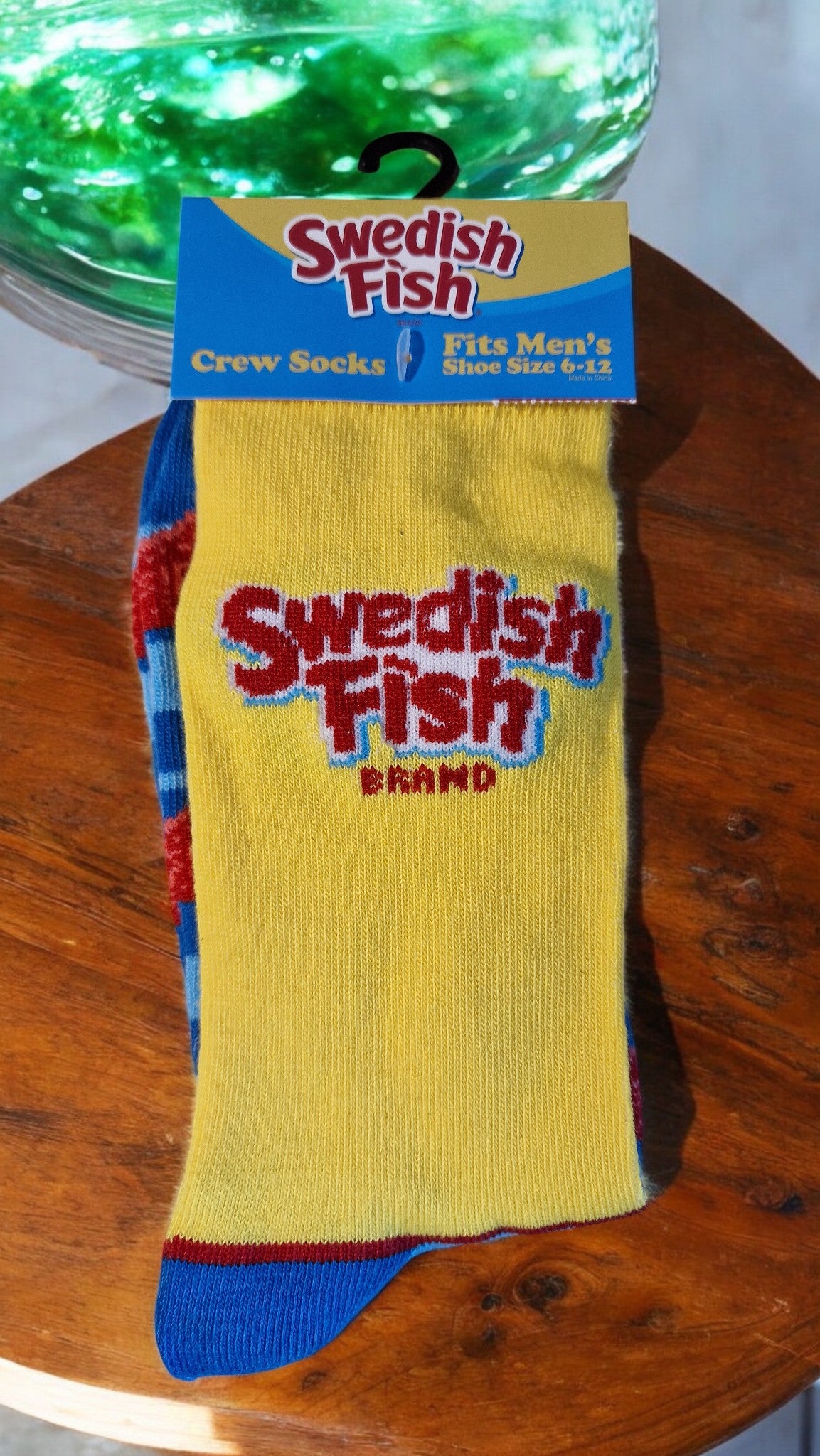 Swedish Fish socks and packaging on a wooden surface with neon lights in the background