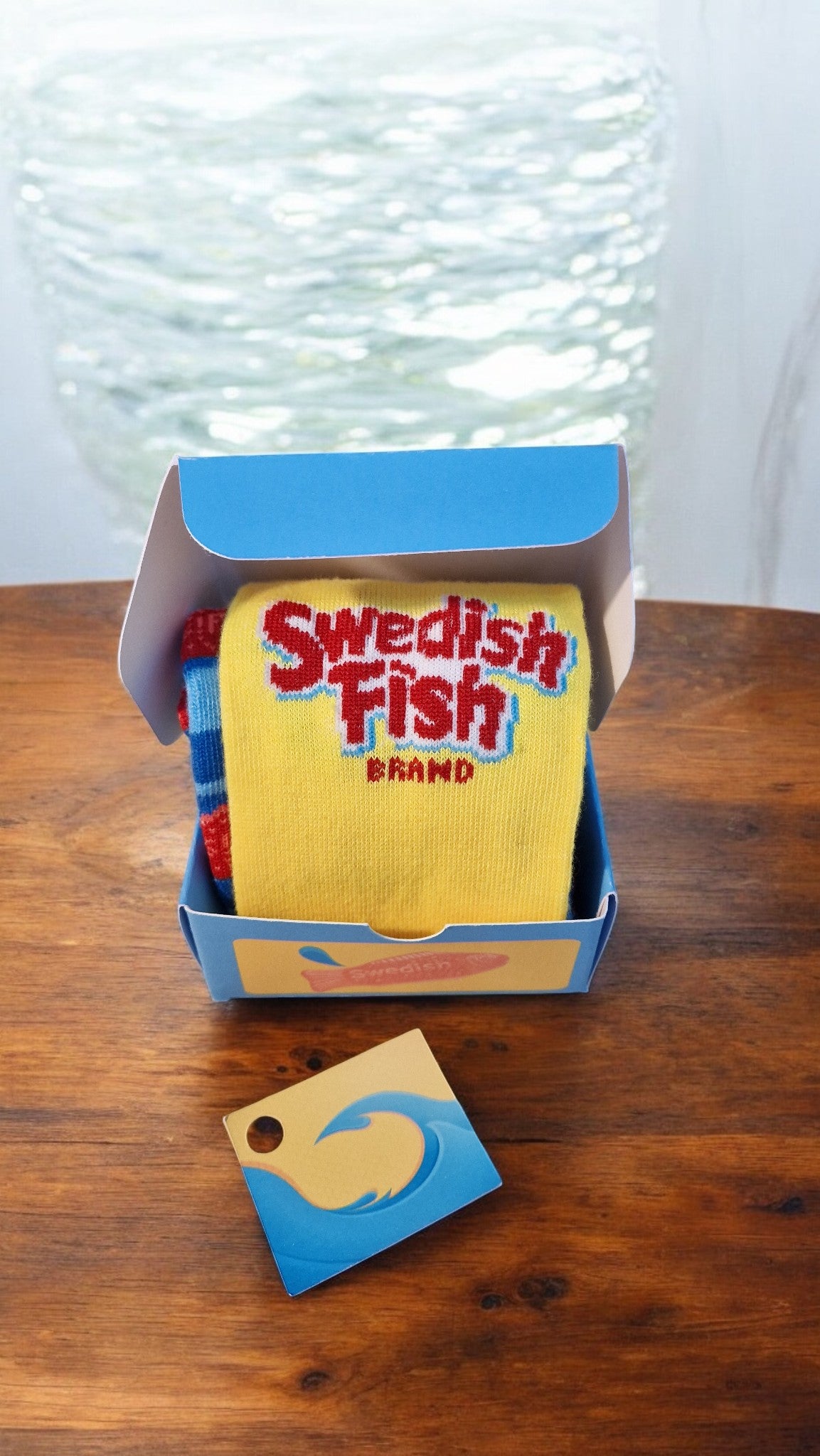 Swedish Fish socks and packaging on a wooden surface with neon lights in the background