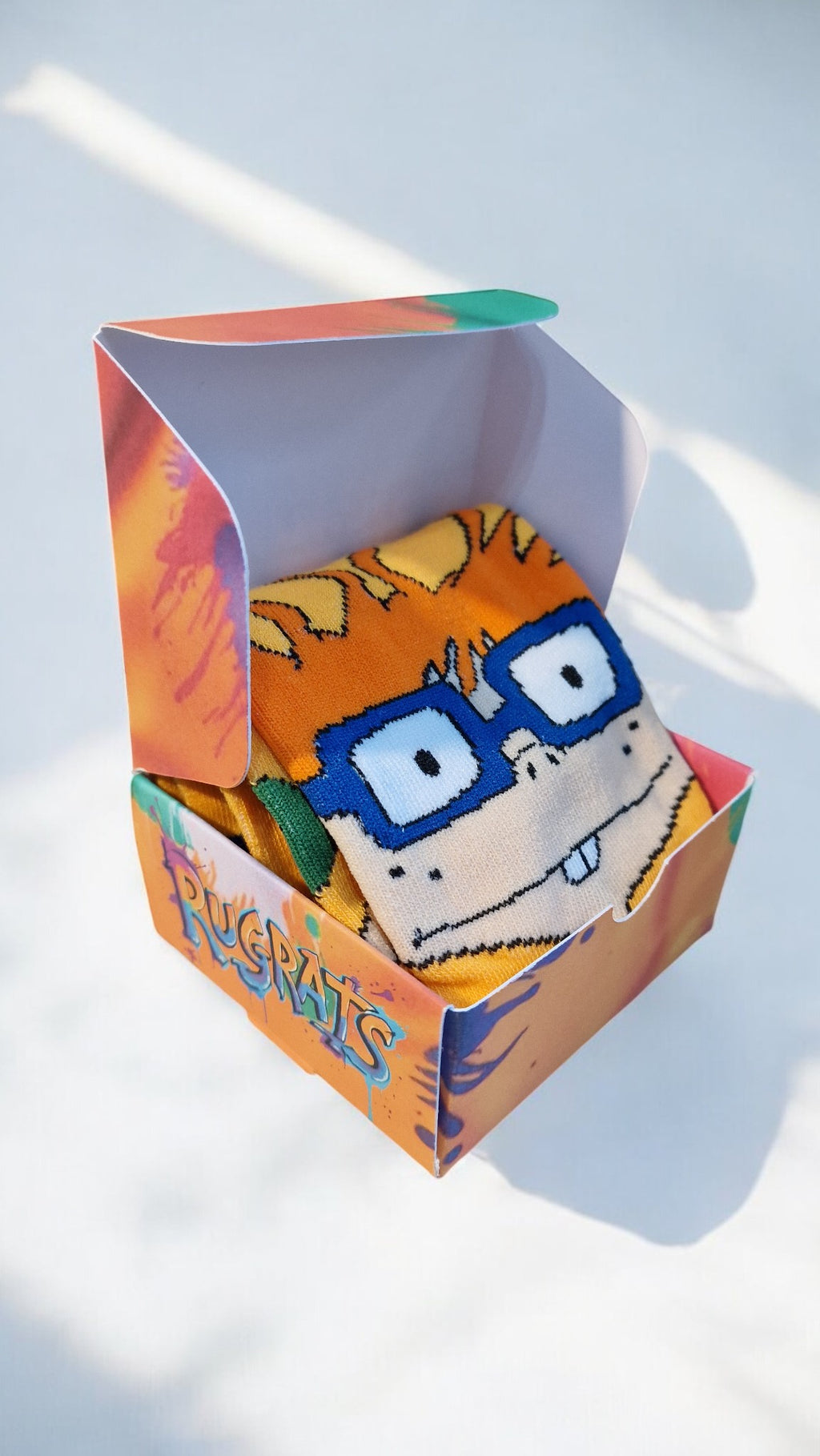 Sock with cartoon character design in a colorful packaging box on a light background